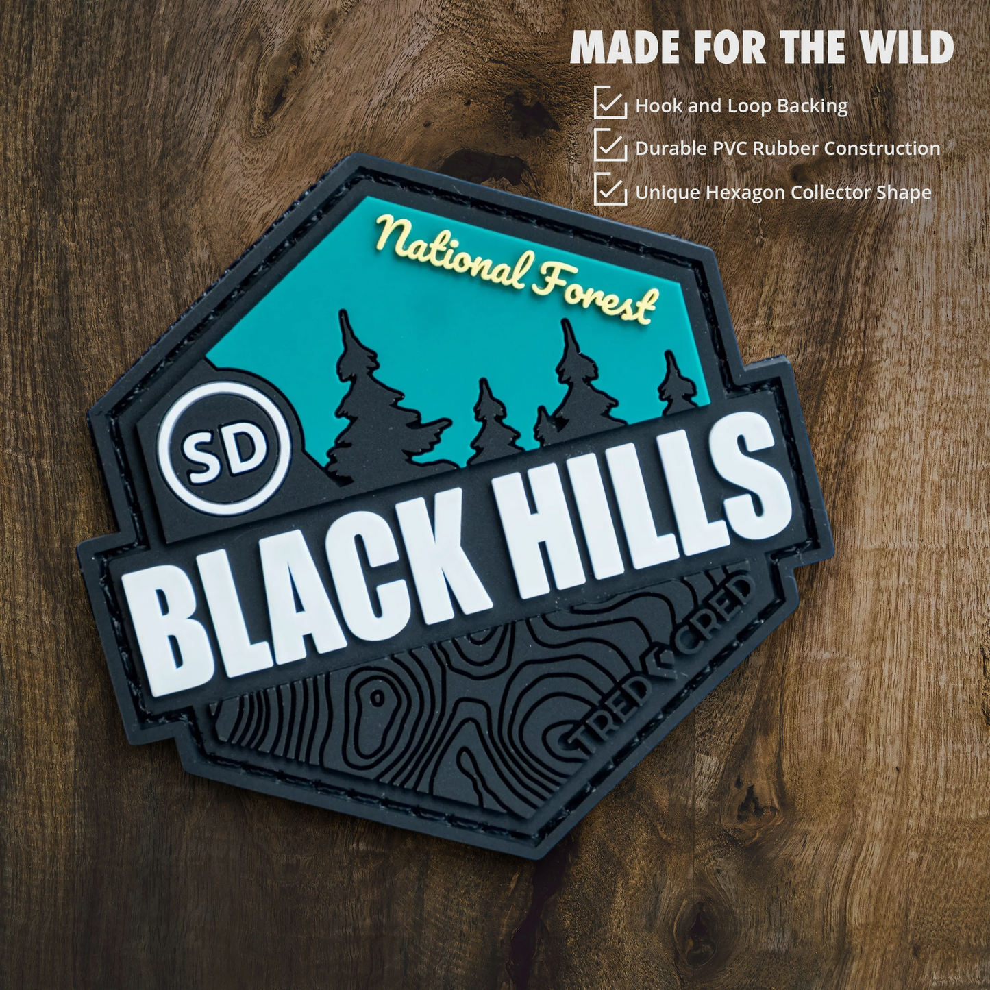 Tred Cred Black Hills National Forest hexagonal PVC patch with teal and black topographic design on wood background.