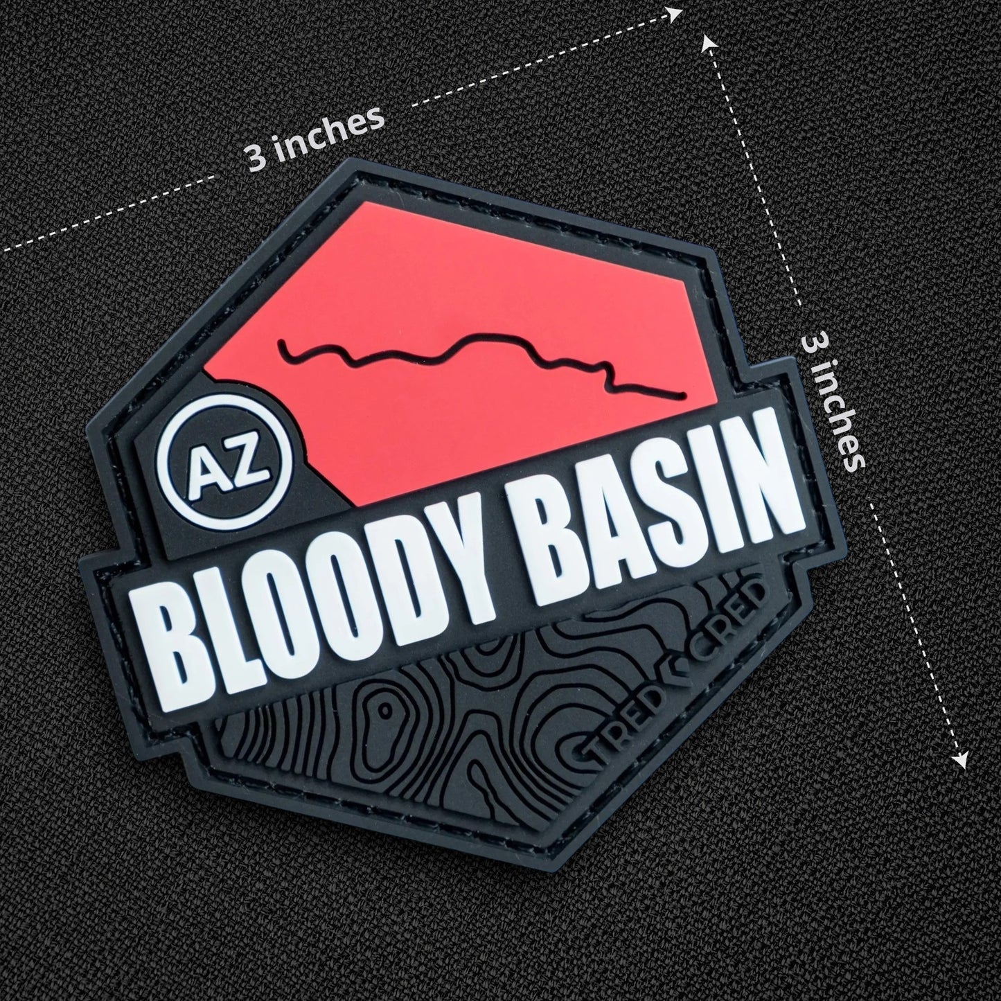 Tred Cred Bloody Basin PVC trail patch with red and black topographic design and AZ badge on a black fabric background