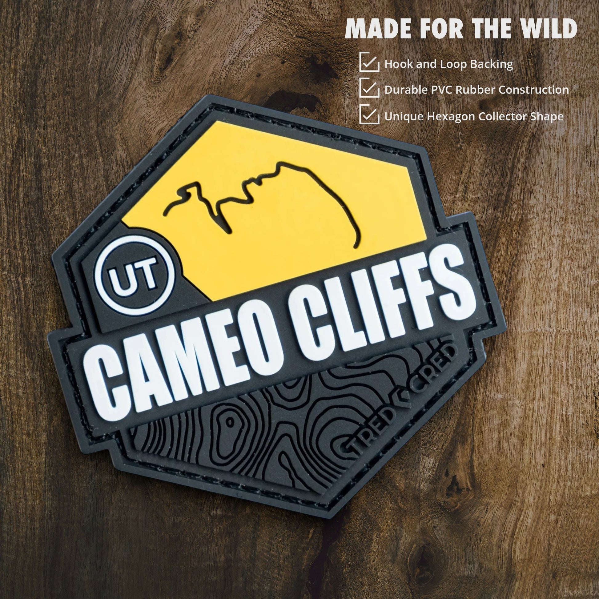 Tred Cred Cameo Cliffs hexagon PVC trail patch with yellow and black design on a wooden background