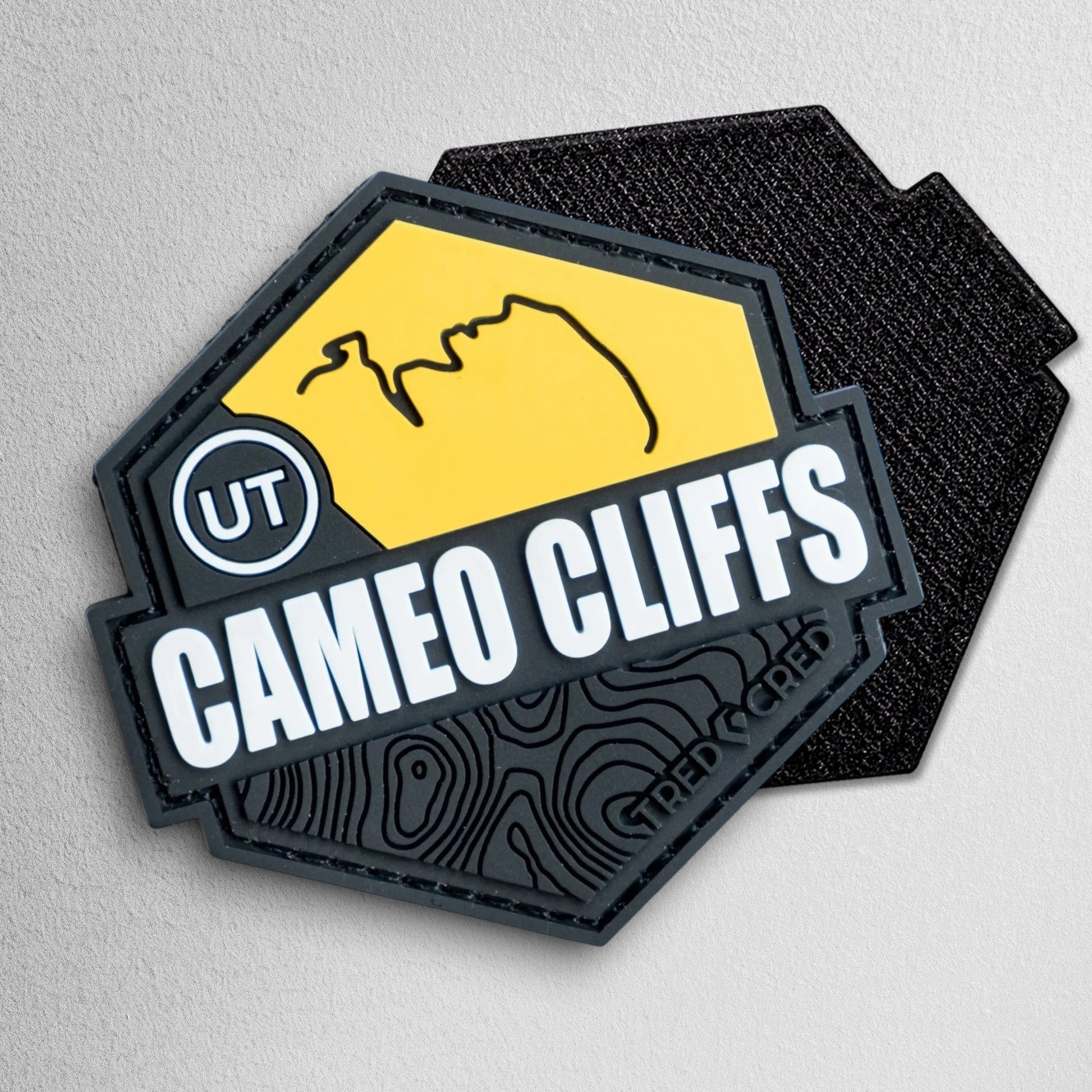 Tred Cred Cameo Cliffs hexagonal PVC trail patch in yellow and black with topographical map design and UT label