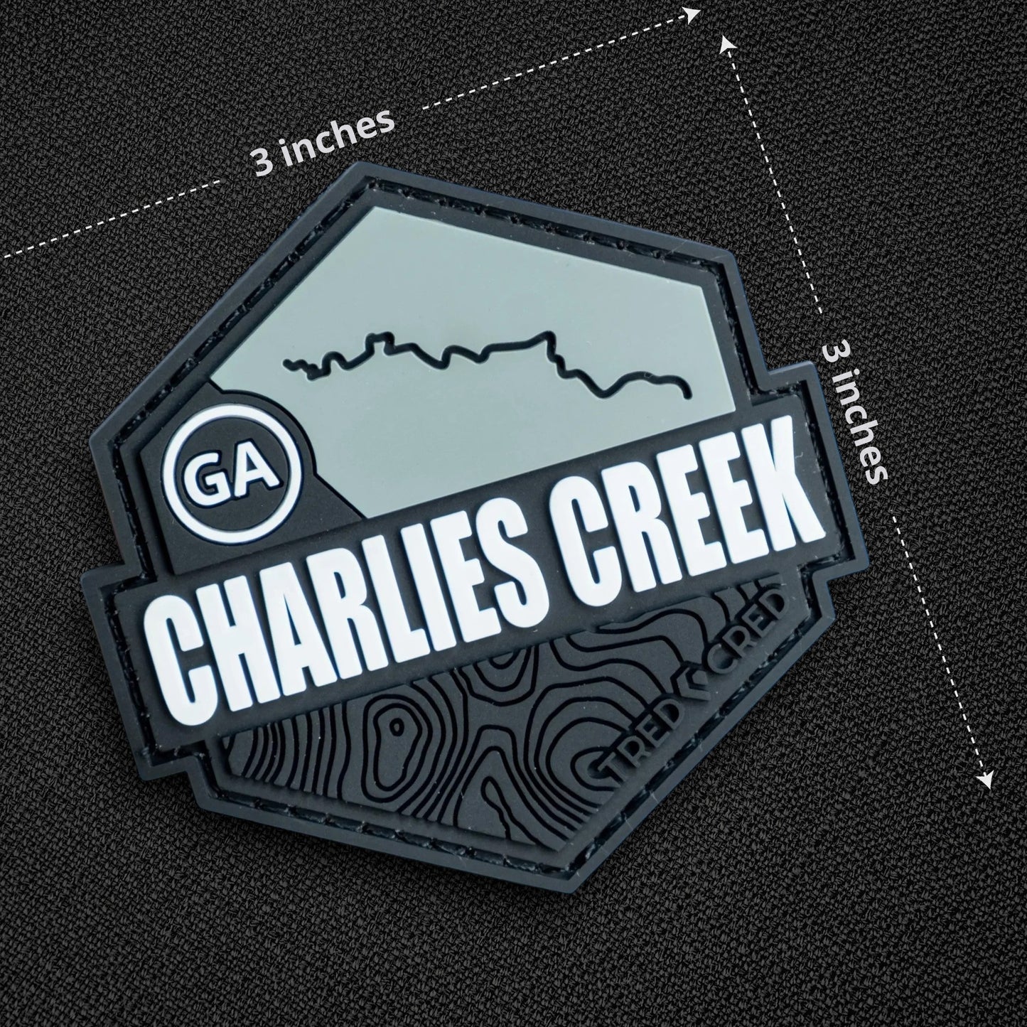 Tred Cred Charlies Creek PVC trail patch with topographic map design and hook and loop backing on black fabric.
