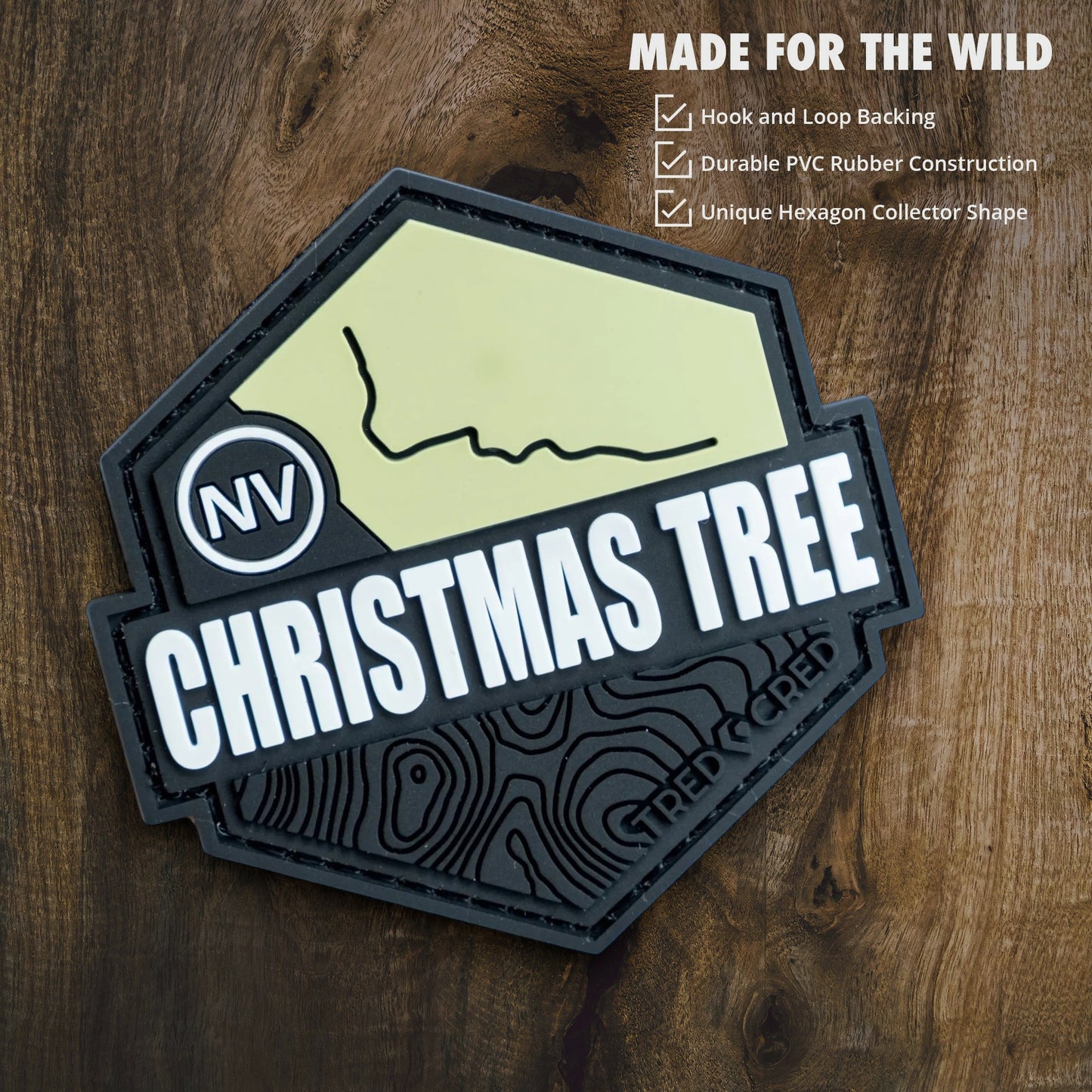 Tred Cred Christmas Tree Pass hexagonal PVC rubber trail patch with hook and loop backing on a wood background.
