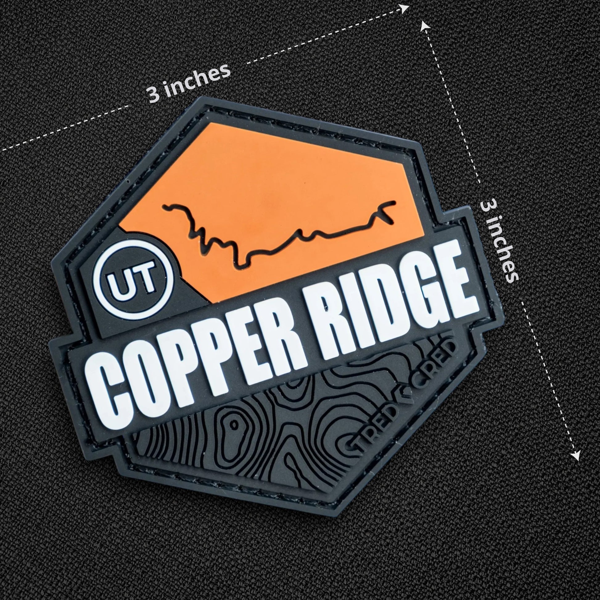 Tred Cred Copper Ridge PVC trail patch with orange and black topographic design and hook and loop backing