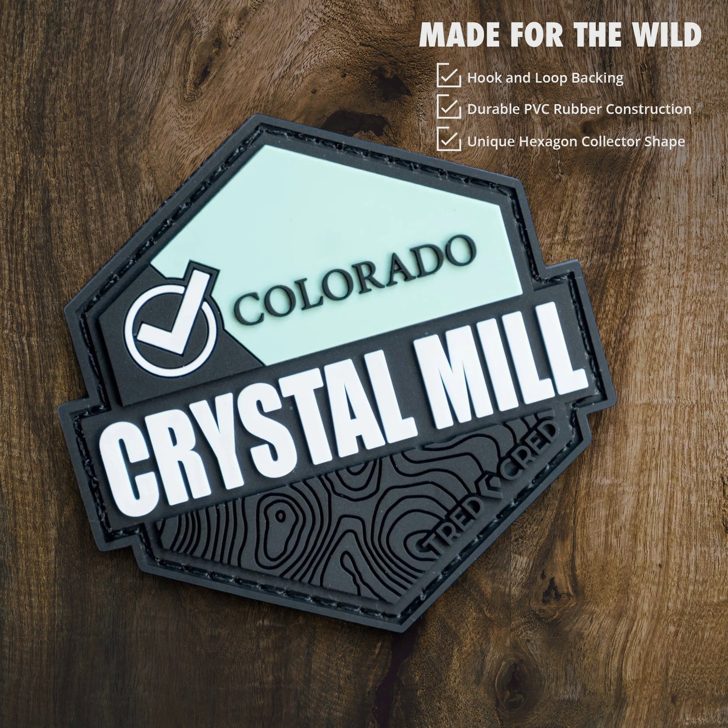 Tred Cred Crystal Mill hexagon PVC patch with hook and loop backing on a wood background.