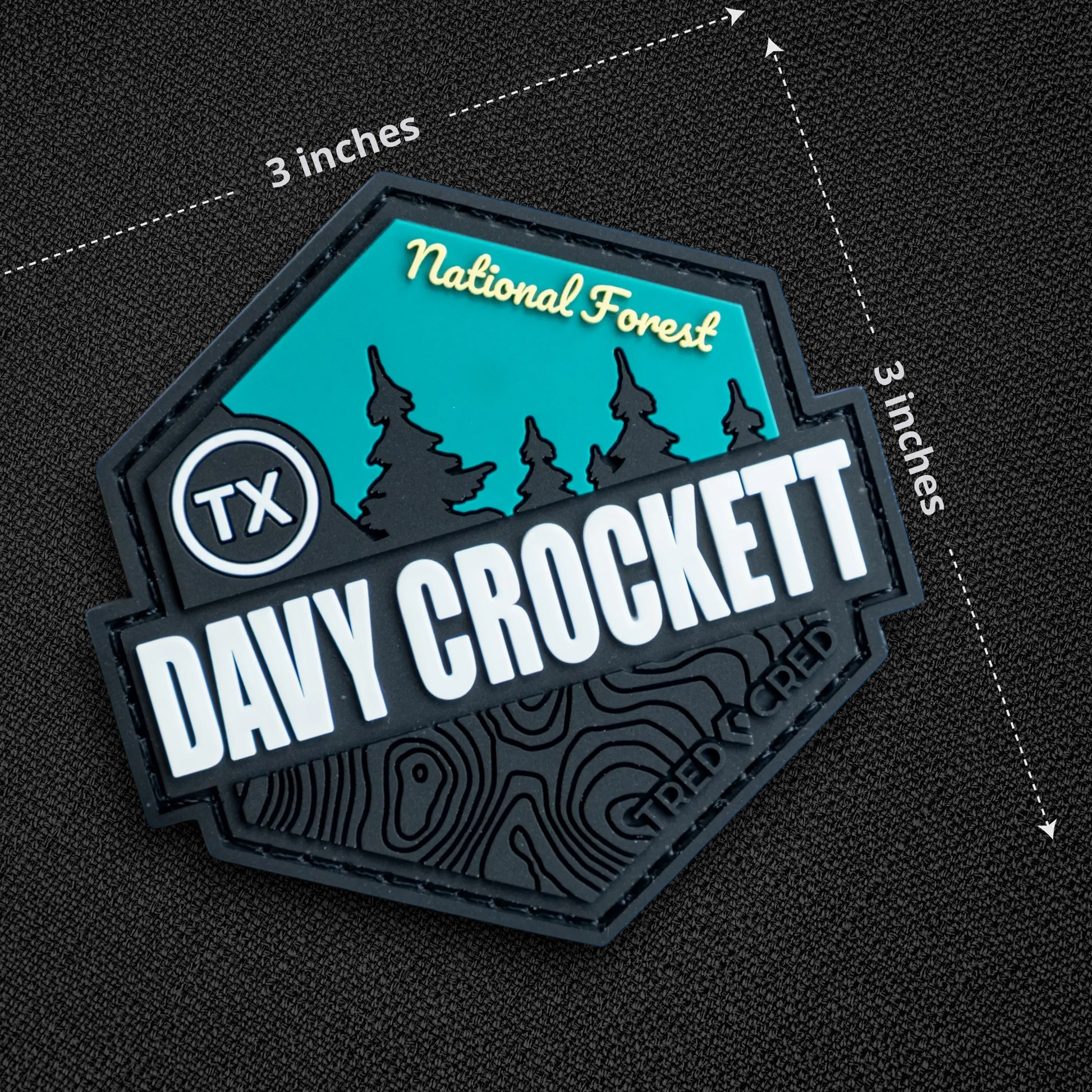 Tred Cred Davy Crockett National Forest PVC patch with teal and black topographic design and hook and loop backing.