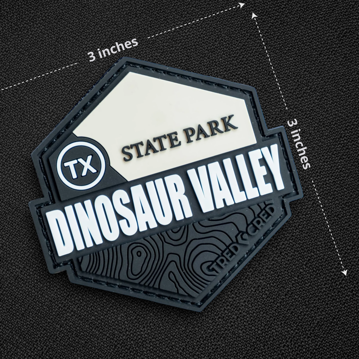 Tred Cred Dinosaur Valley State Park PVC patch with white and black topographic design and hook and loop backing.