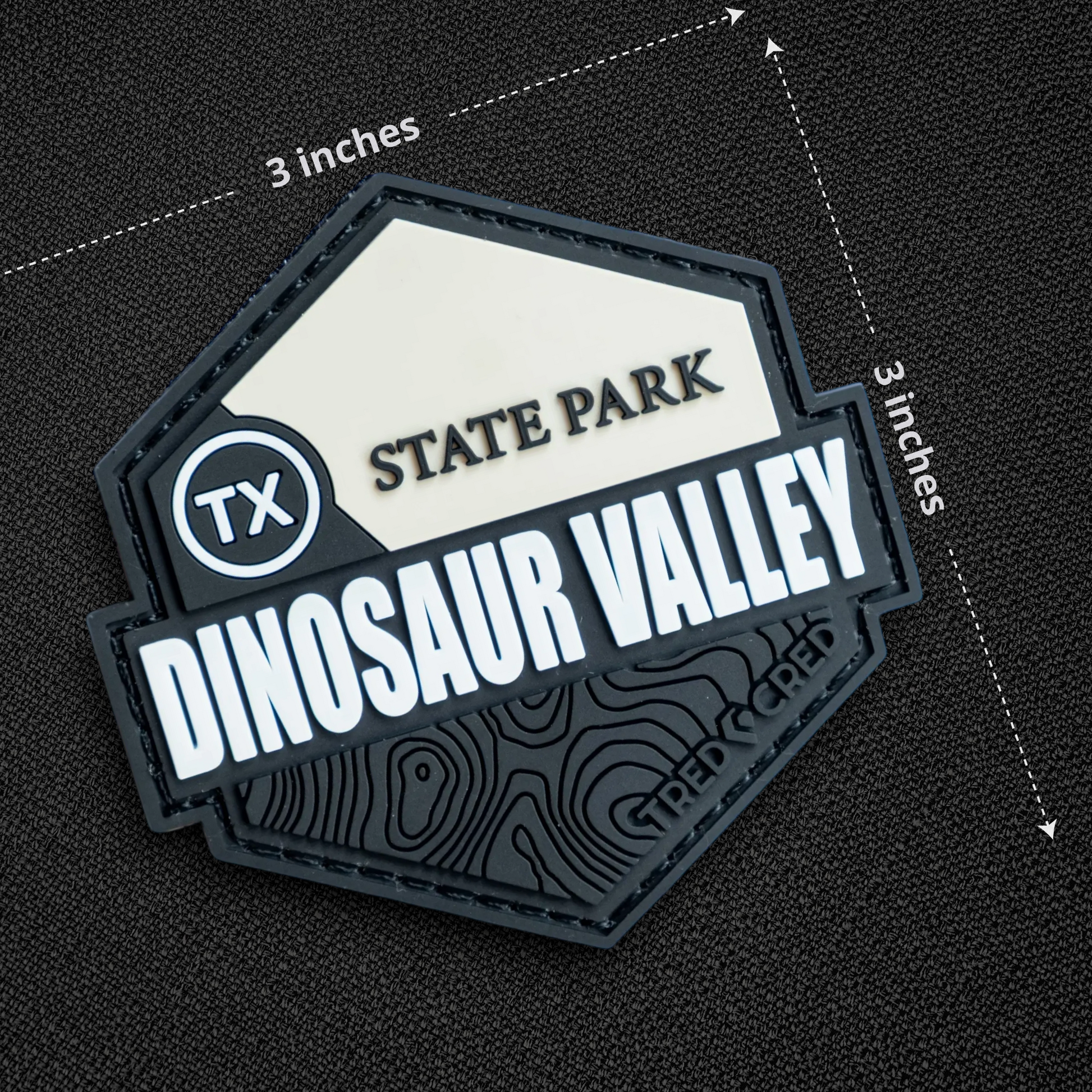 Tred Cred Dinosaur Valley State Park PVC patch with white and black topographic design and hook and loop backing.