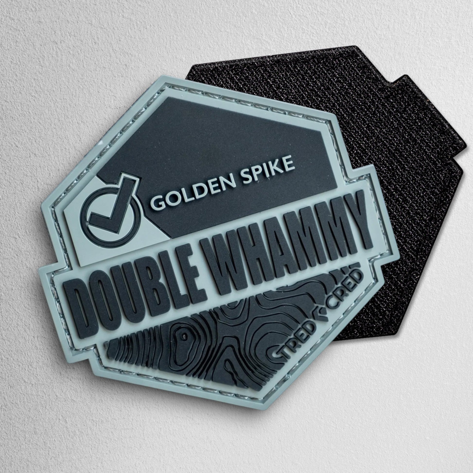 Tred Cred Double Whammy hexagonal PVC trail patch in grey and black with topographic map detail and hook backing