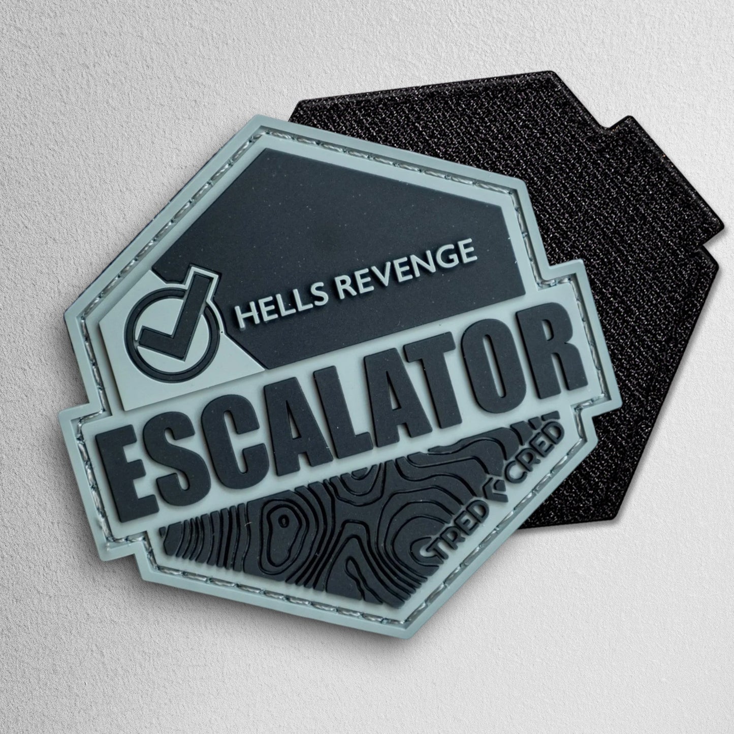 Tred Cred Escalator PVC trail patch with Hells Revenge text and topographic map design in grey and black