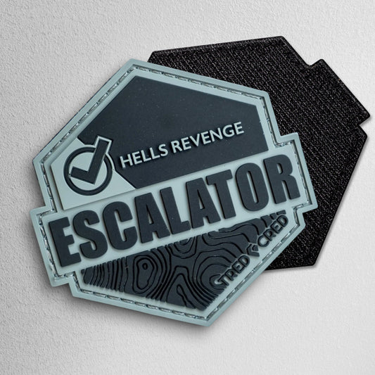 Tred Cred Escalator PVC trail patch with Hells Revenge text and topographic map design in grey and black