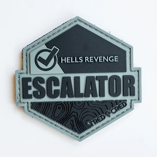 Tred Cred Escalator trail patch in grey and black PVC rubber with topographic map design and hook and loop backing.