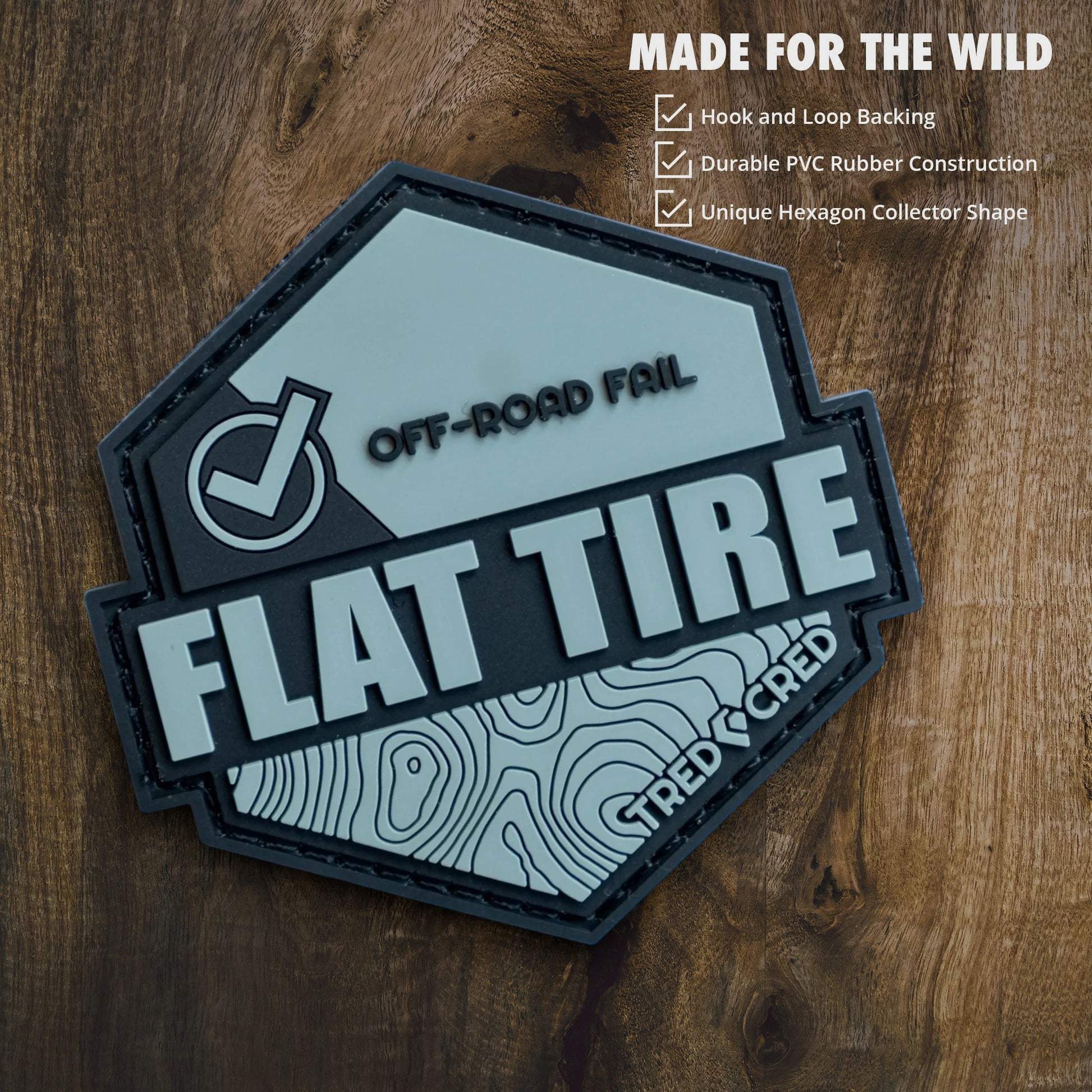 Tred Cred Flat Tire PVC patch with off-road topography design and hook and loop backing on a grey background.