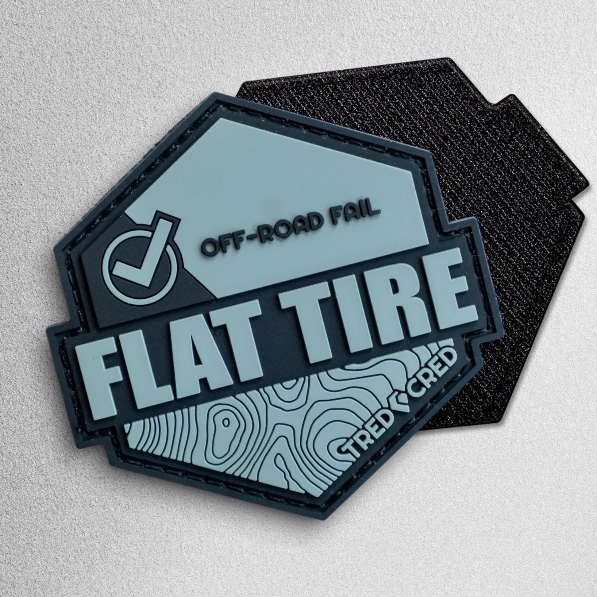 Tred Cred Flat Tire PVC patch in grey and black with a topographic map design and hook and loop backing.