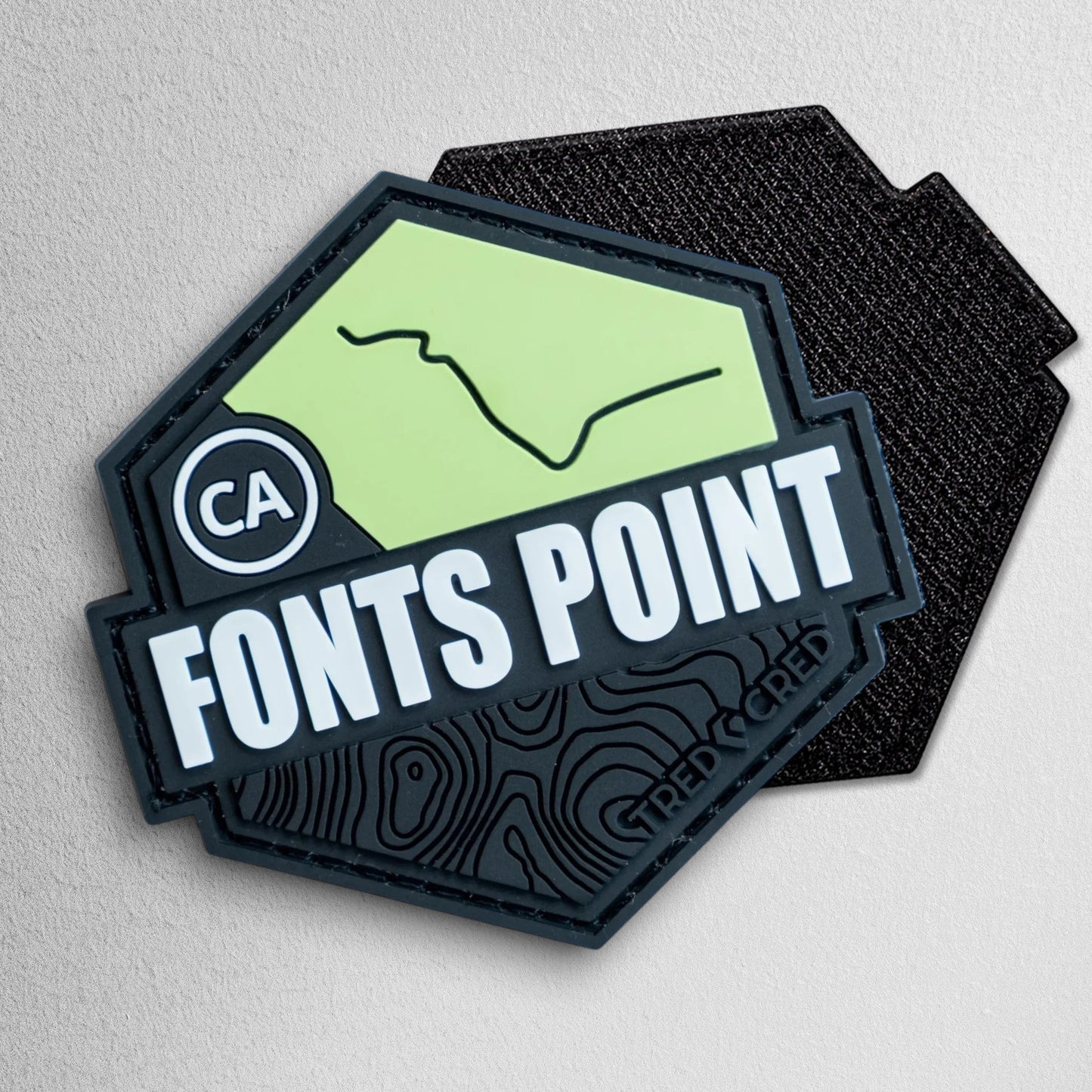 Tred Cred Fonts Point hexagonal PVC trail patch with green topographic map design and black hook and loop backing.
