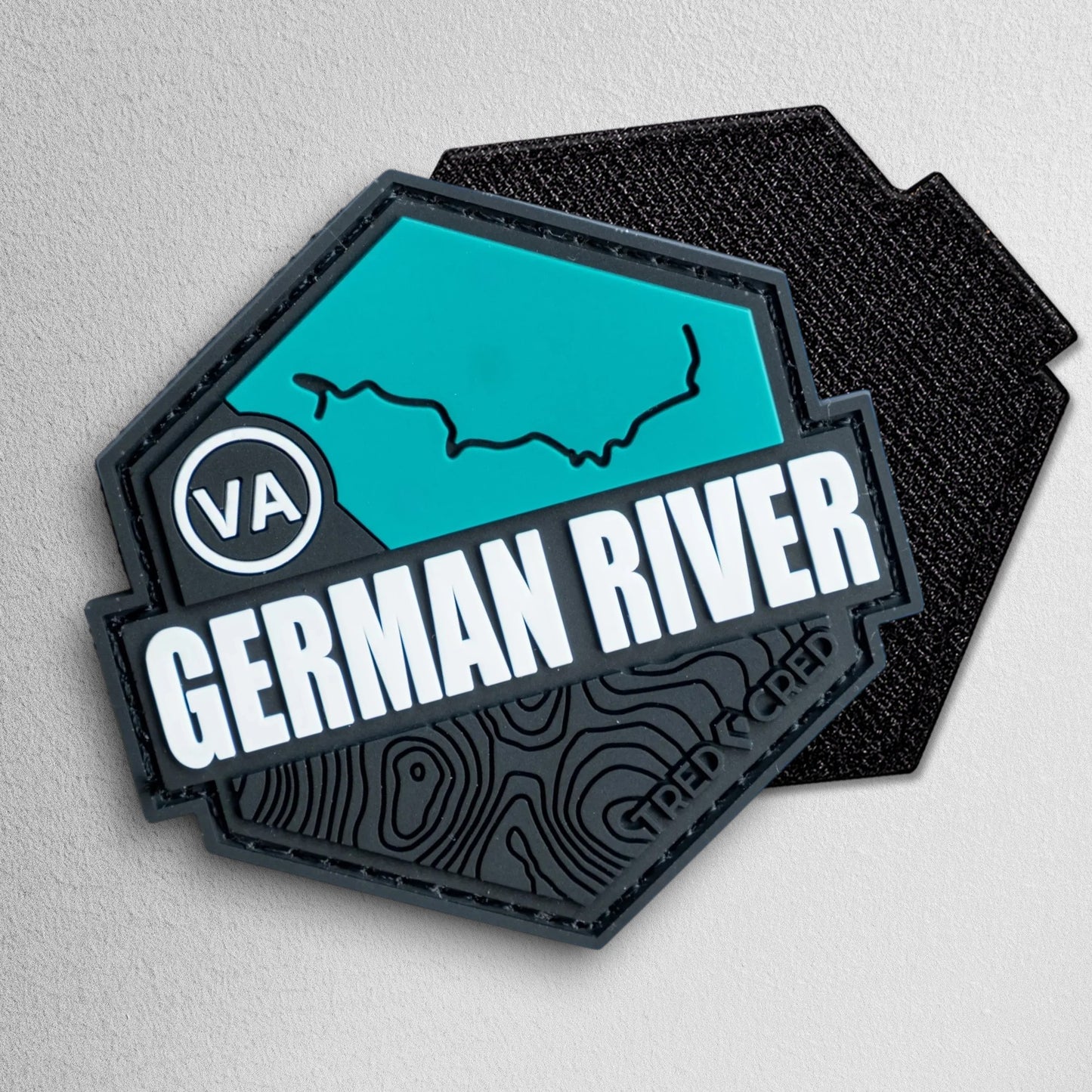 Tred Cred German River trail patch in teal and black PVC rubber with a hexagonal shape and hook and loop backing.