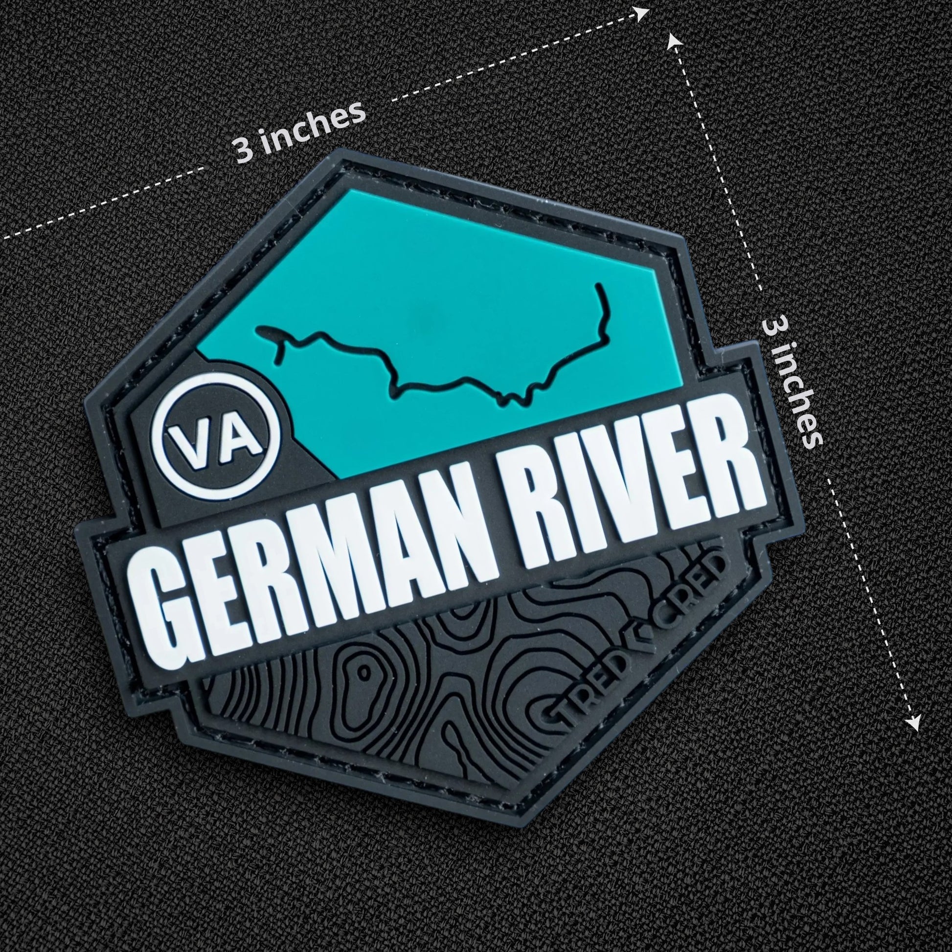 Tred Cred German River trail patch in teal and black PVC rubber with hook and loop backing, 3x3 inch hexagonal shape.