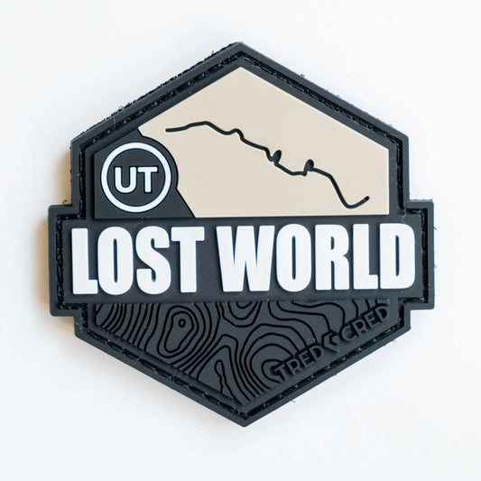 Tred Cred Lost World PVC trail patch with a hexagonal shape, beige mountain outline, and black topographic detail.