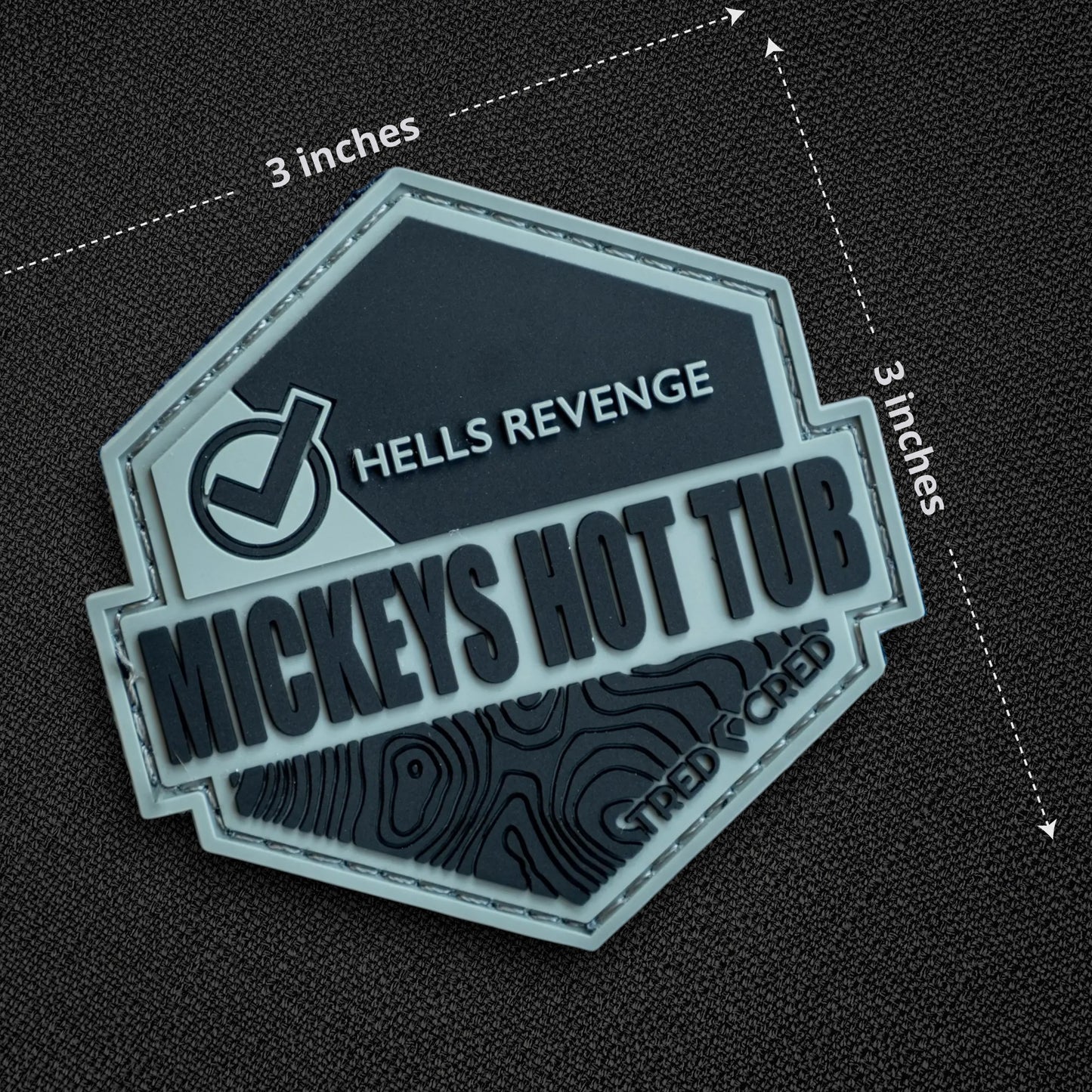 Tred Cred Mickeys Hot Tub PVC trail patch in grey and black with topographic map design and hook and loop backing.