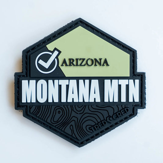 Tred Cred Montana Mountain PVC patch with a hexagonal shape, olive green and black design, and topographic details.