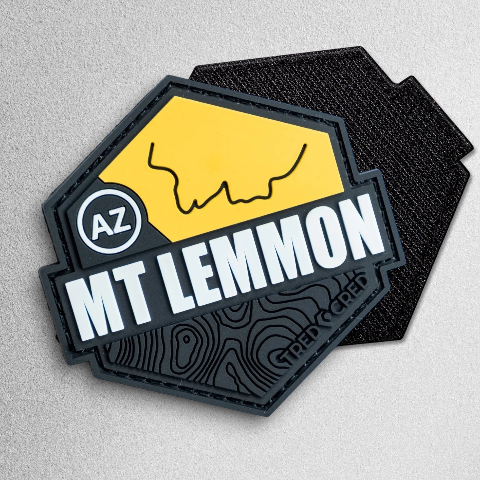 Tred Cred Mount Lemmon PVC trail patch in yellow and black with topographic map design and hook and loop backing.