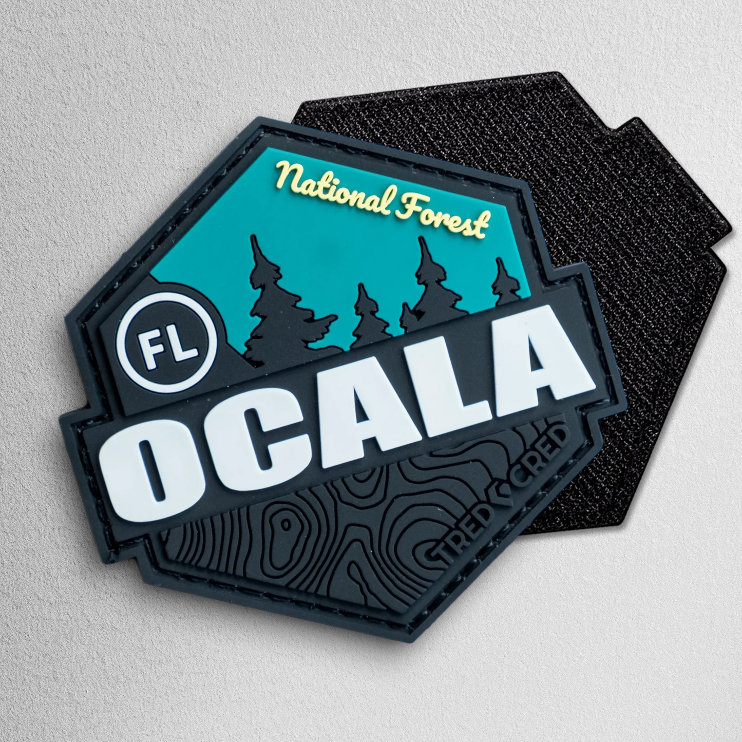 Tred Cred Ocala National Forest PVC patch with teal and black design, featuring topographic lines and hook backing.