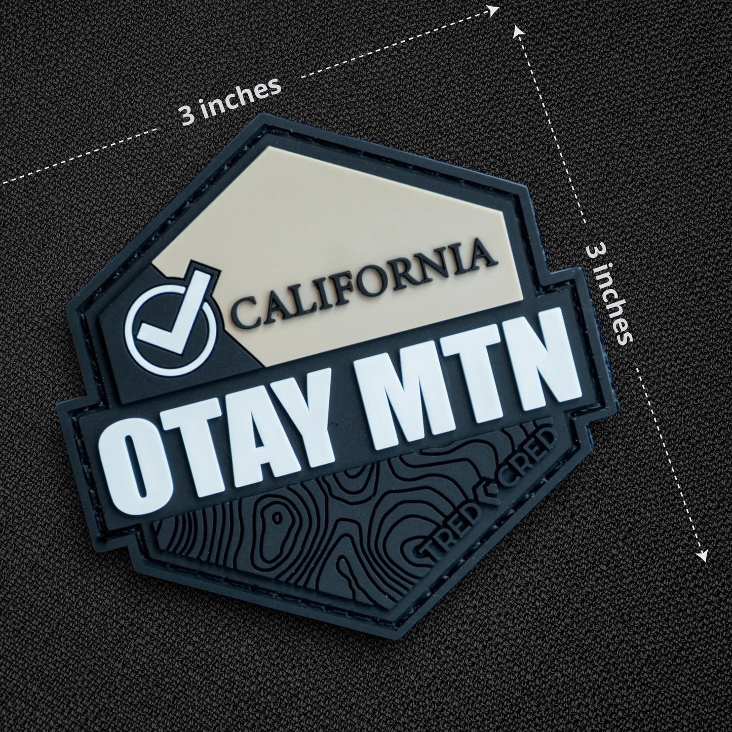 Tred Cred Otay Mountain PVC patch with black and beige topographic design and hook and loop backing.