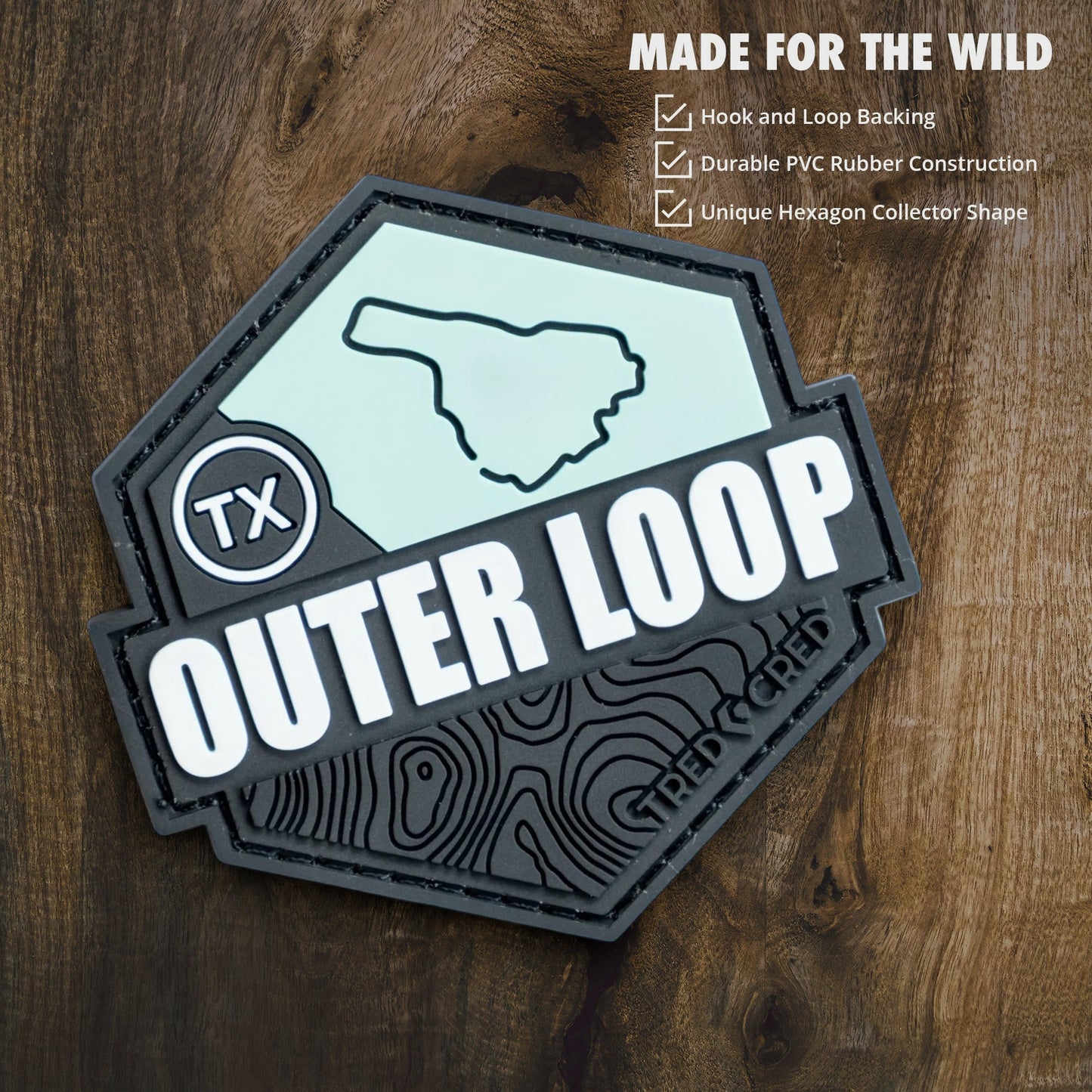 Tred Cred Outer Loop hexagon PVC trail patch with hook and loop backing on a wooden background