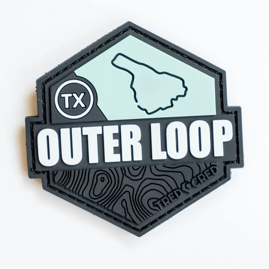 Tred Cred Outer Loop hexagonal PVC trail patch in black and light blue with TX badge and topographic map detail.