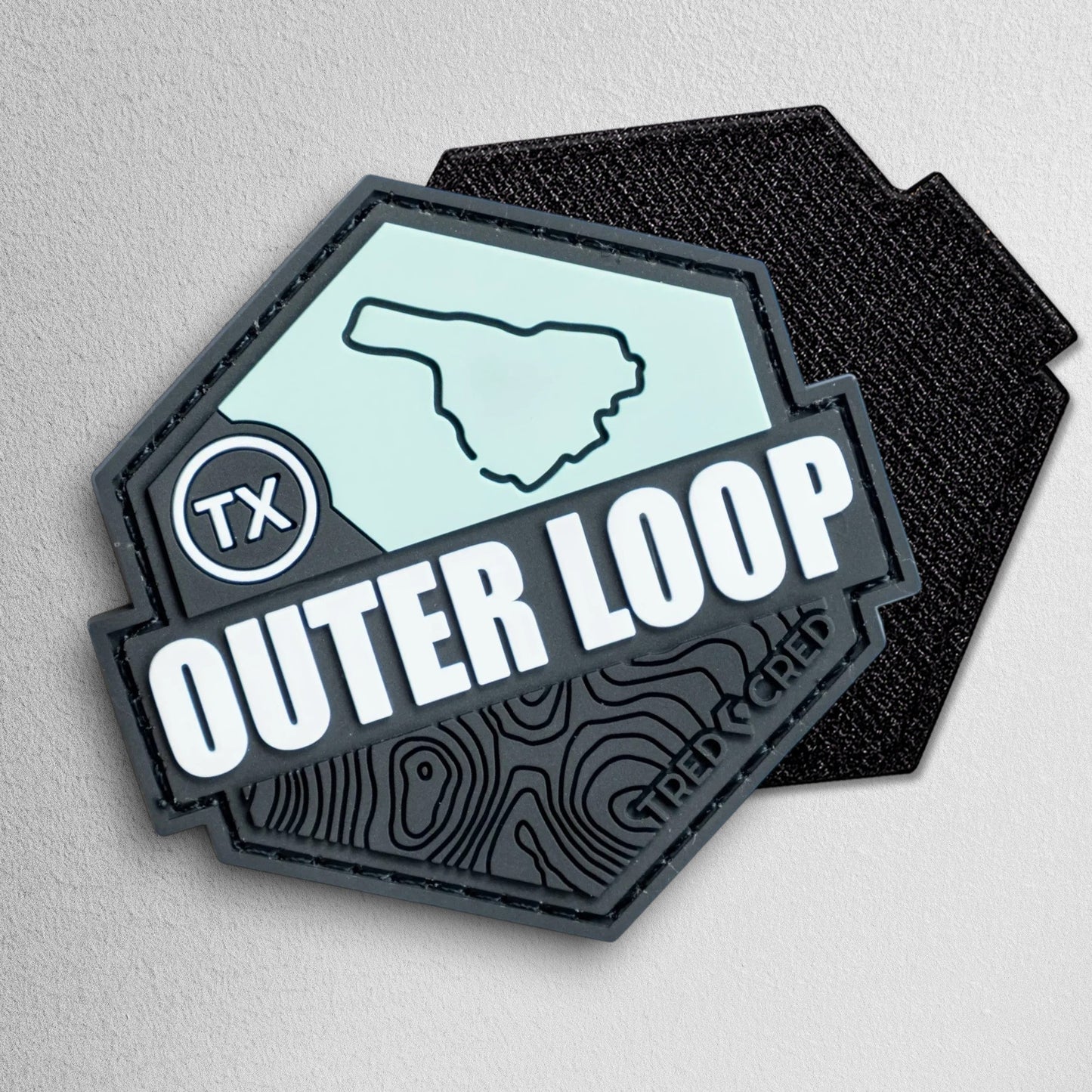 Tred Cred Outer Loop hexagonal PVC trail patch with topographic map design and Texas TX badge in black and mint green.