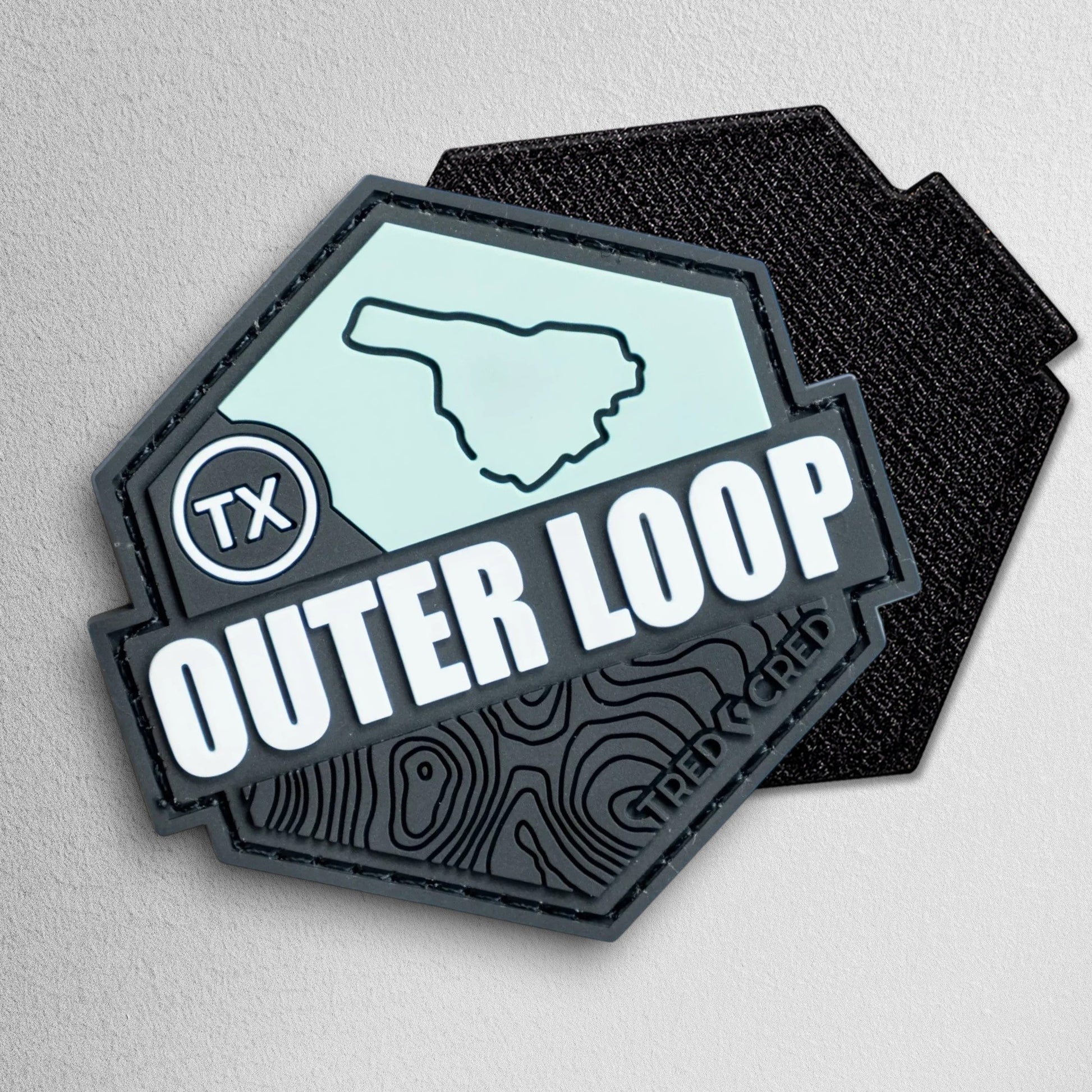 Tred Cred Outer Loop hexagonal PVC trail patch with topographic map design and Texas TX badge in black and mint green.