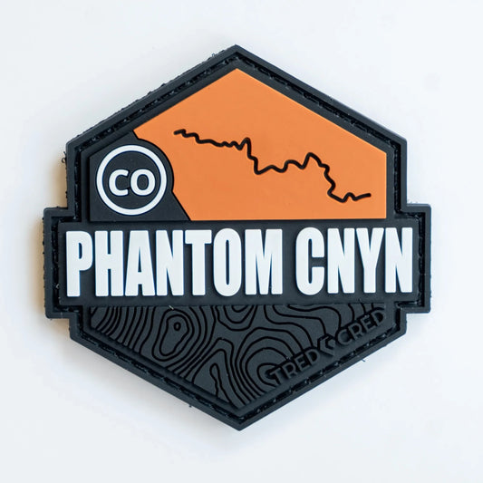 Tred Cred Phantom Canyon PVC trail patch with orange and black topographic design and hook and loop backing.