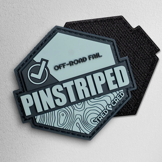 Tred Cred Pinstriped hexagonal PVC patch in grey and black with off-road fail text and topographical map design.