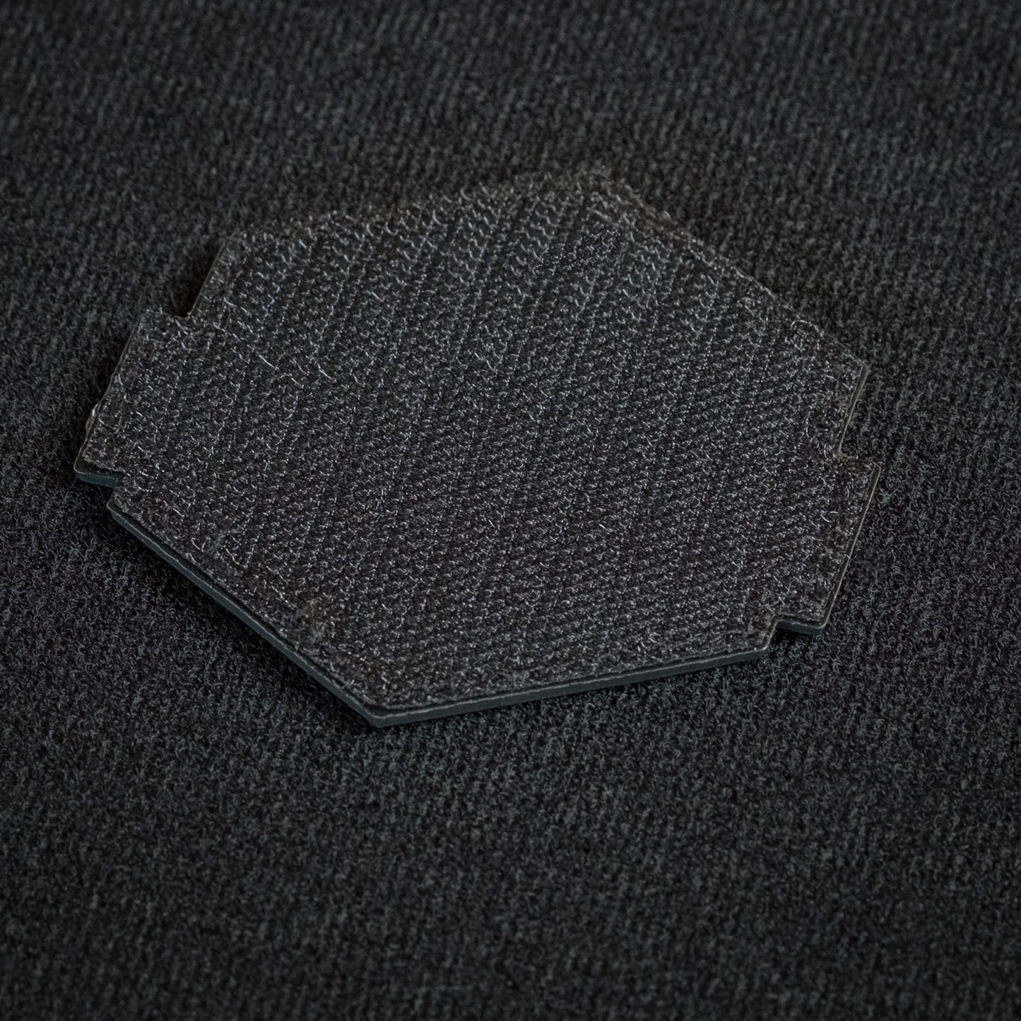 Tred Cred Rainbow Falls trail patch showing the black hook and loop backing on a textured fabric surface.
