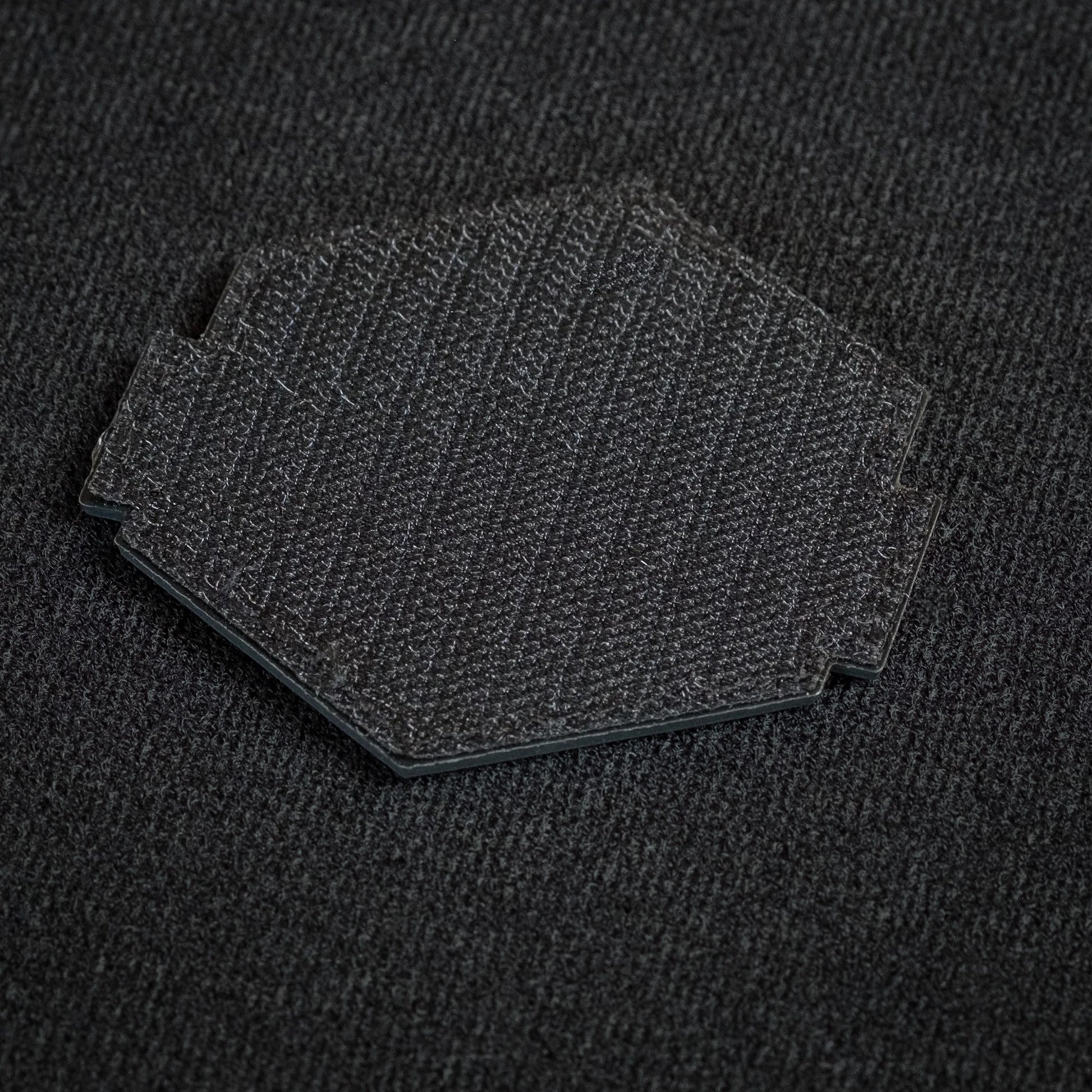 Tred Cred Rainbow Falls trail patch showing the black hook and loop backing on a textured fabric surface.