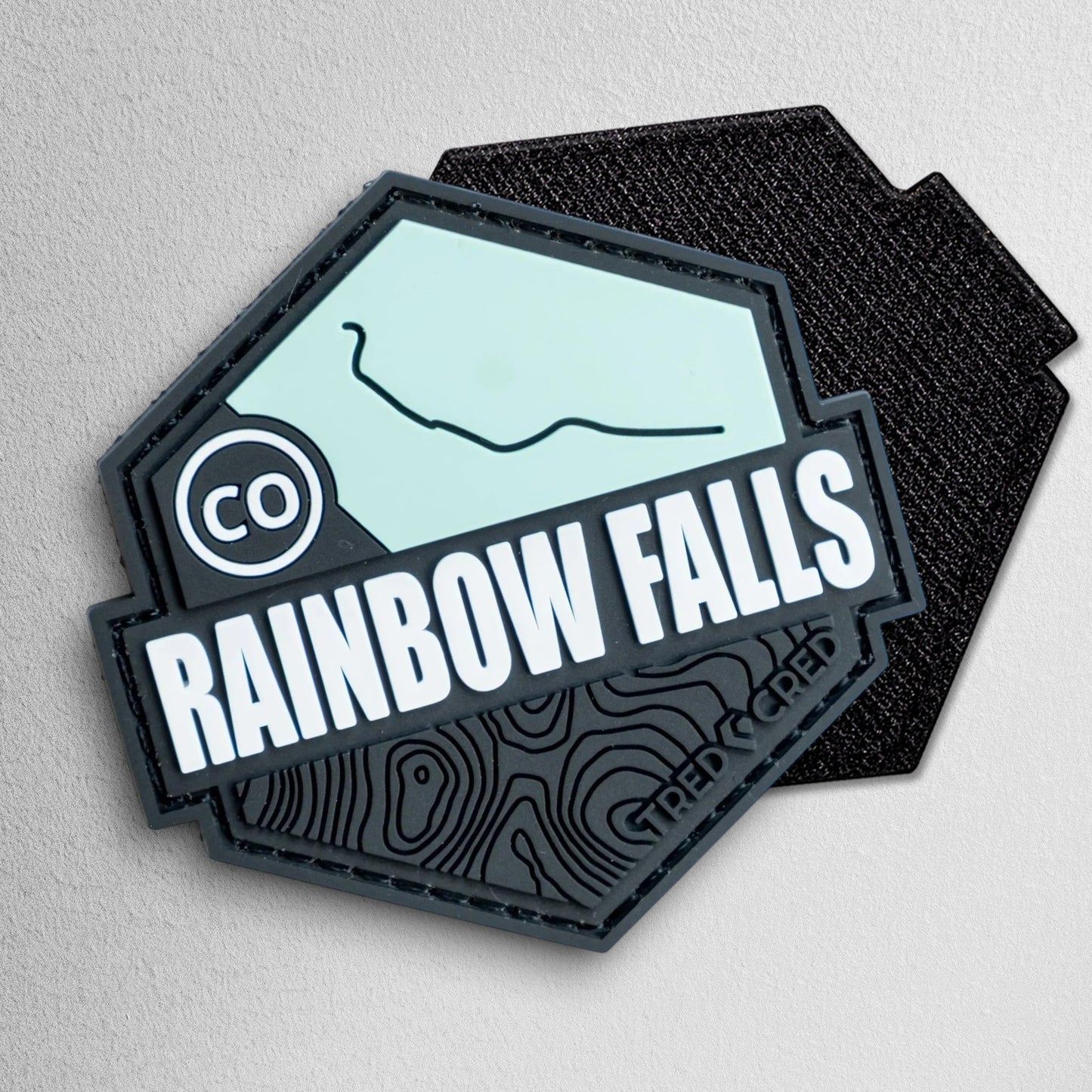 Tred Cred Rainbow Falls PVC trail patch with hook and loop backing, featuring a topographic map design.