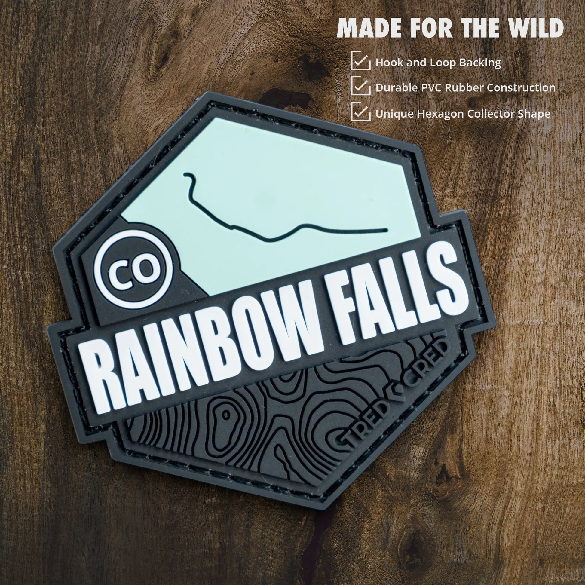 Tred Cred Rainbow Falls hexagon PVC patch with hook and loop backing on a wooden background