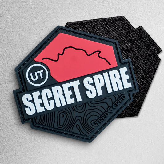 Tred Cred Secret Spire trail patch in red and black PVC rubber with a hexagonal shape and topographic map design.