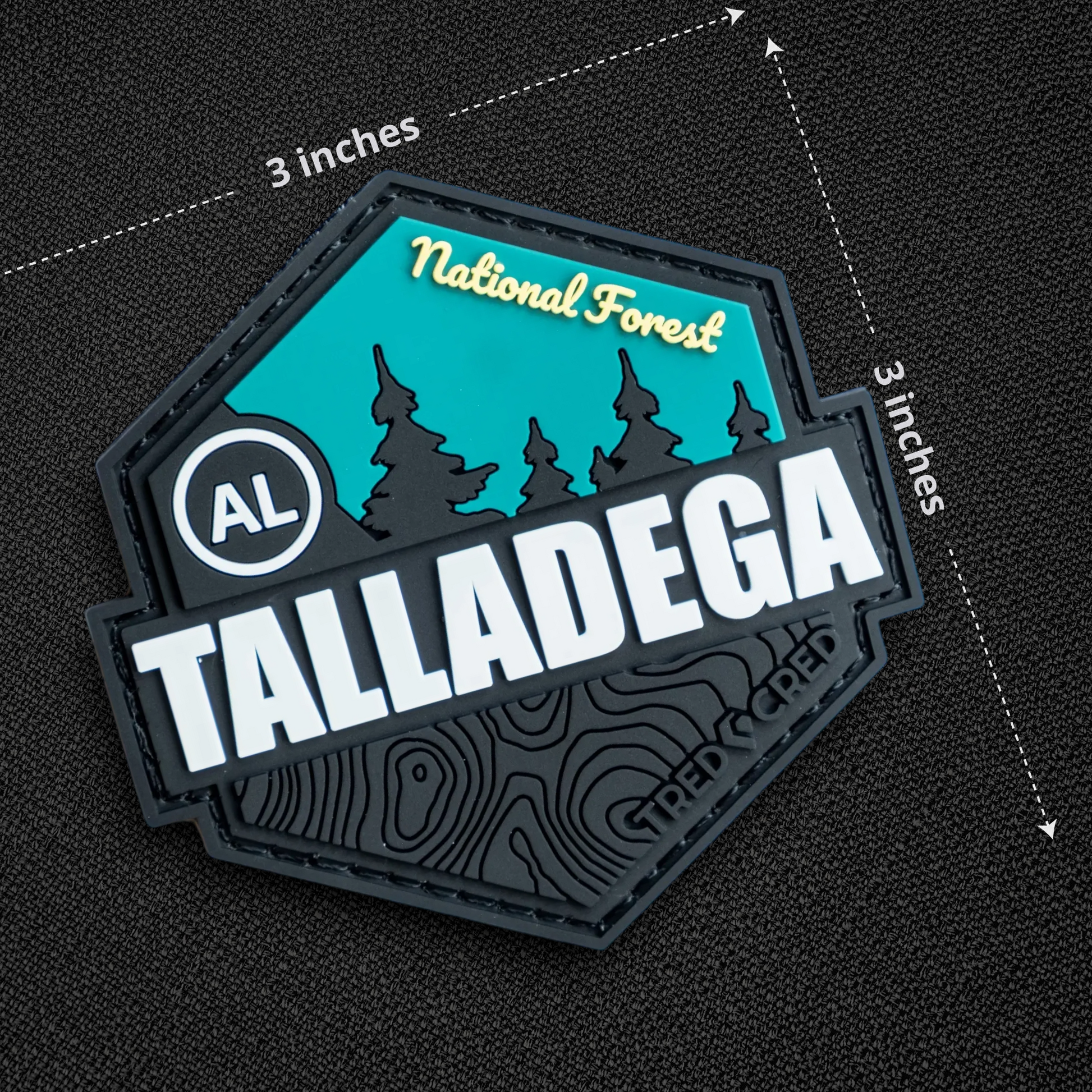 Tred Cred Talladega National Forest PVC patch with teal and black topographic design and hook and loop backing.