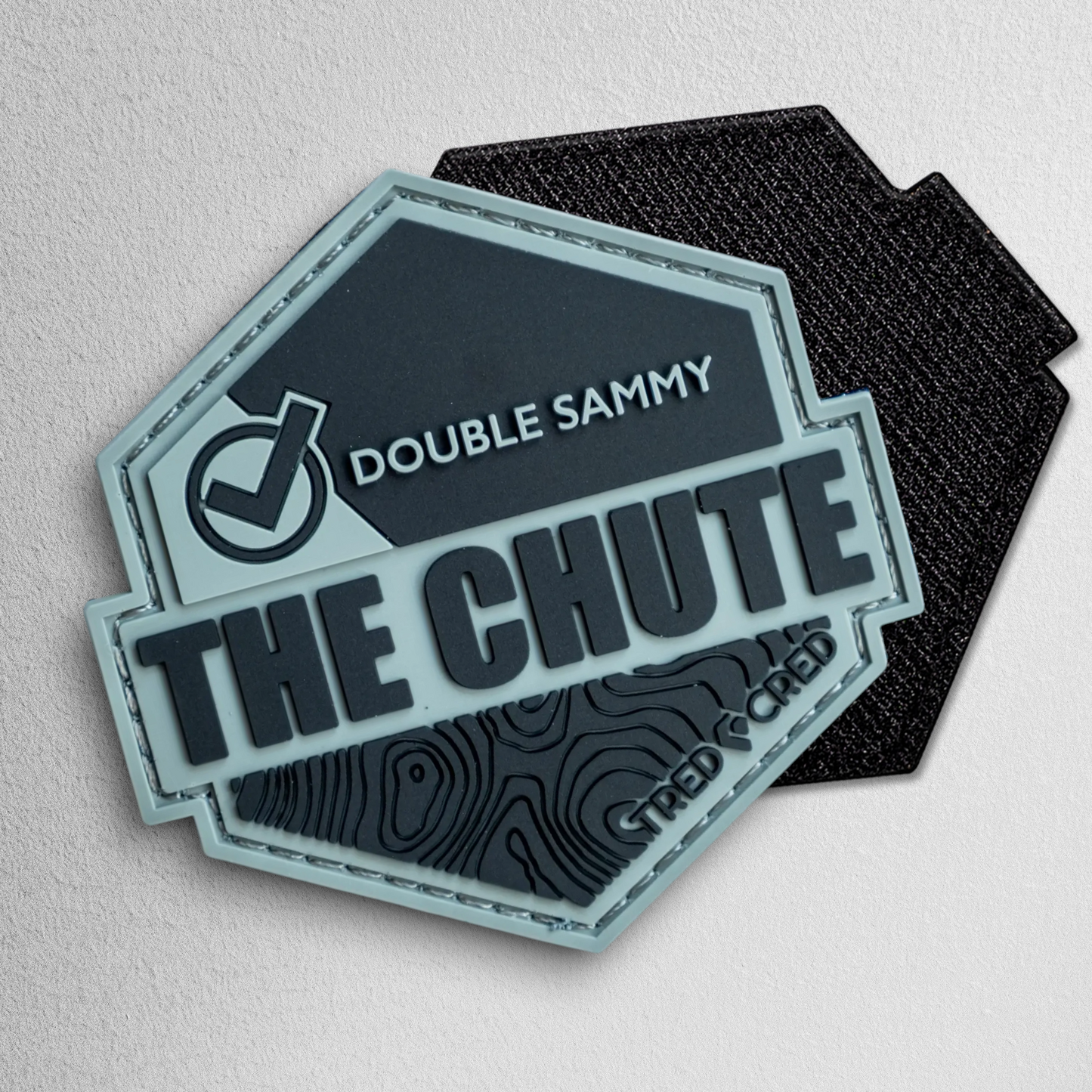 Tred Cred The Chute hexagonal PVC trail patch in grey and black with hook and loop backing.