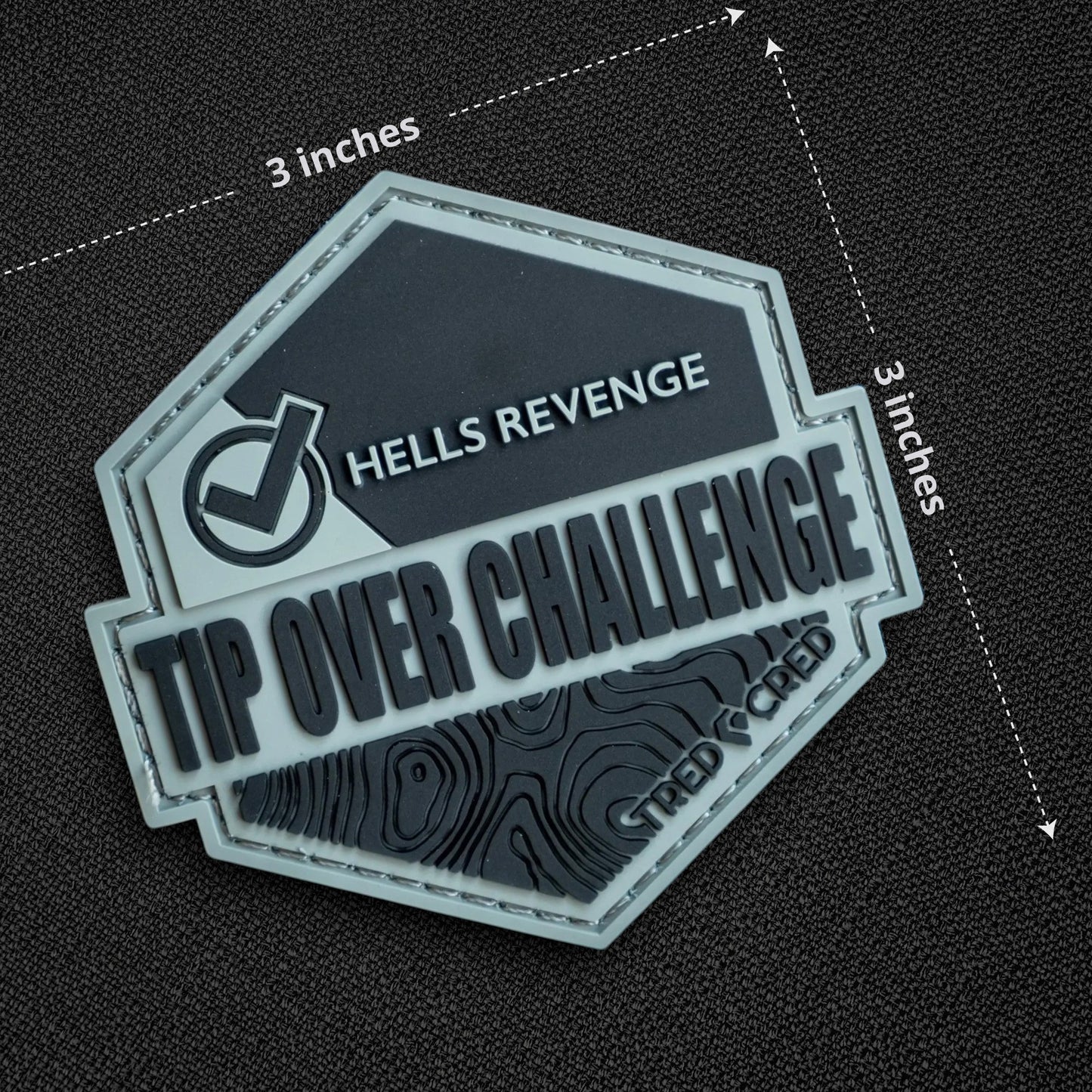 Tred Cred Tip Over Challenge PVC patch with Hells Revenge text and topographic map design on a hook and loop backing.
