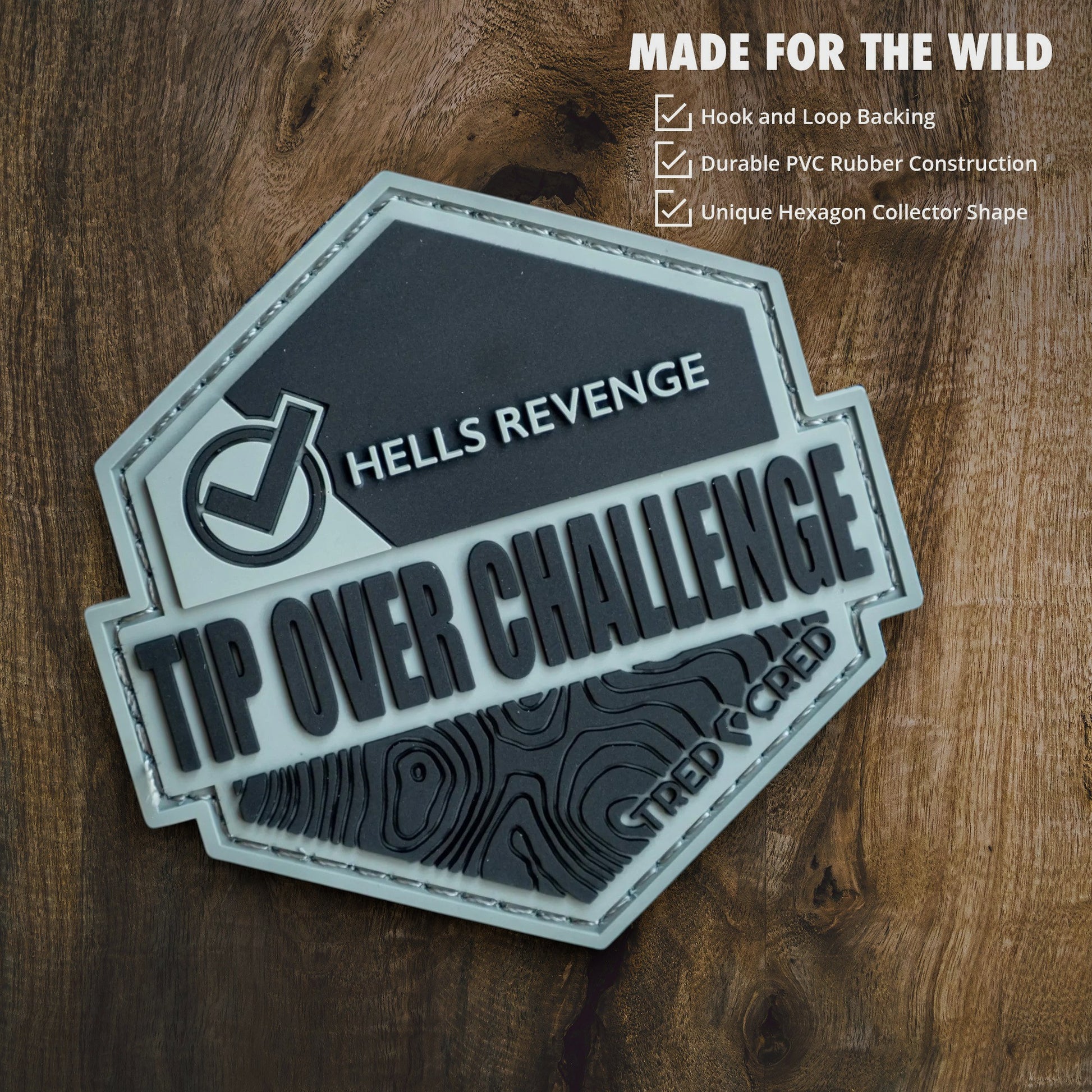 Tred Cred Tip Over Challenge hexagon PVC rubber patch with hook and loop backing on a wooden background