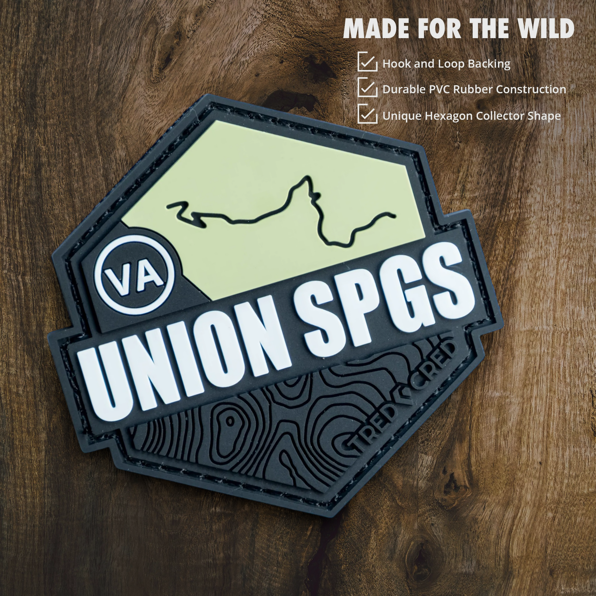 Tred Cred Union Springs hexagon PVC trail patch with hook and loop backing on a wooden background