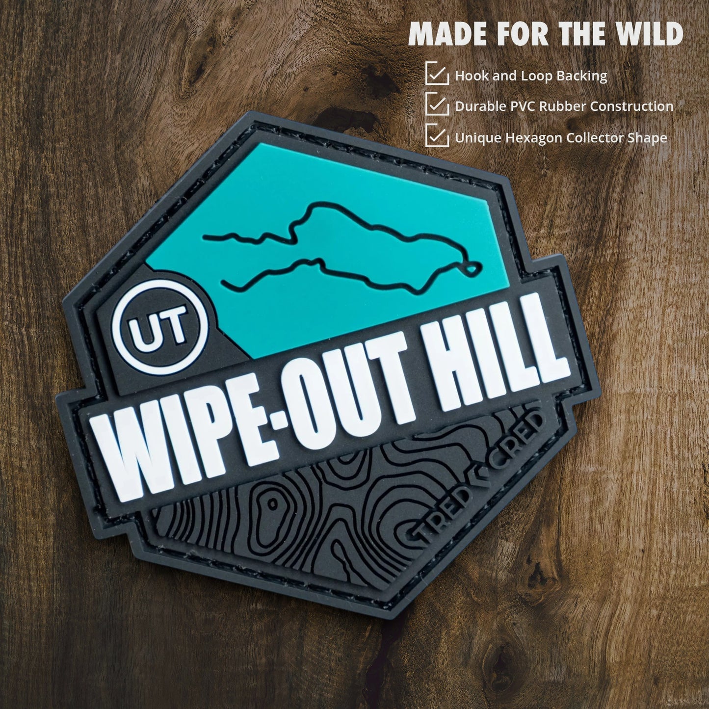 Tred Cred Wipe-Out Hill trail patch in teal and black PVC rubber with hook and loop backing and topographic design.