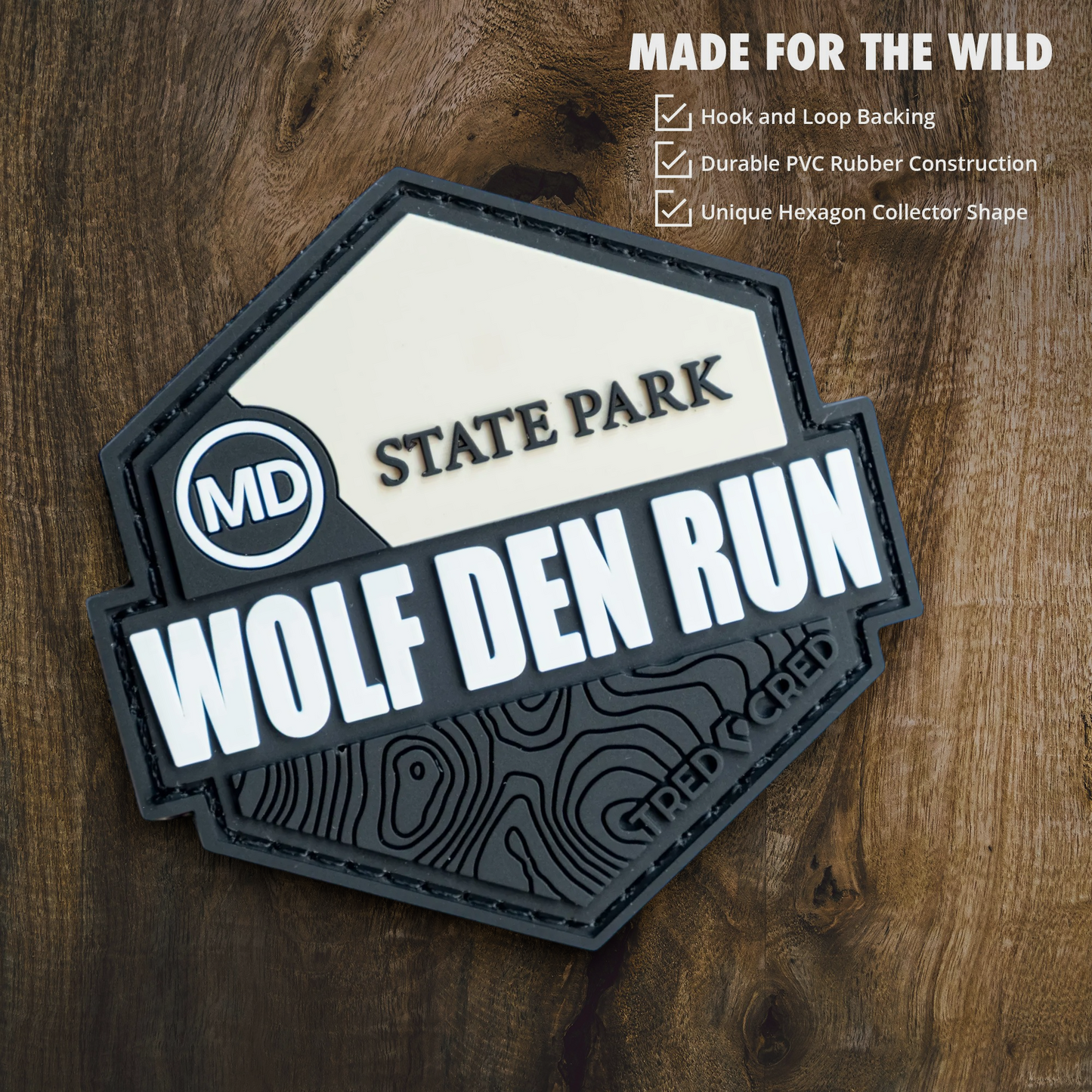 Tred Cred Wolf Den Run State Park hexagonal PVC patch with hook and loop backing on a wooden background