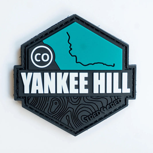 Tred Cred Yankee Hill PVC trail patch with teal and black topographic design and hook and loop backing