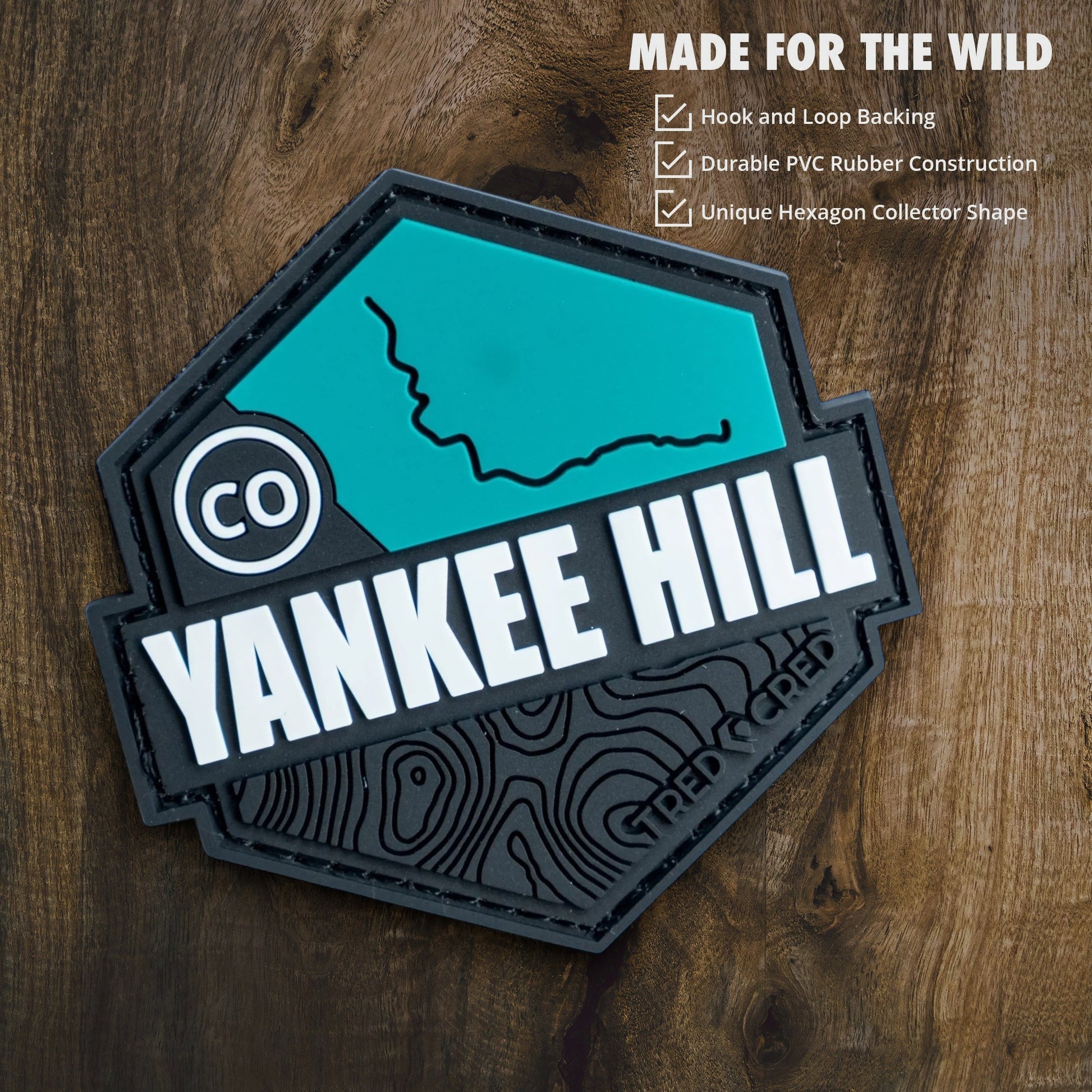 Tred Cred Yankee Hill hexagon PVC rubber trail patch with hook and loop backing on a wooden background
