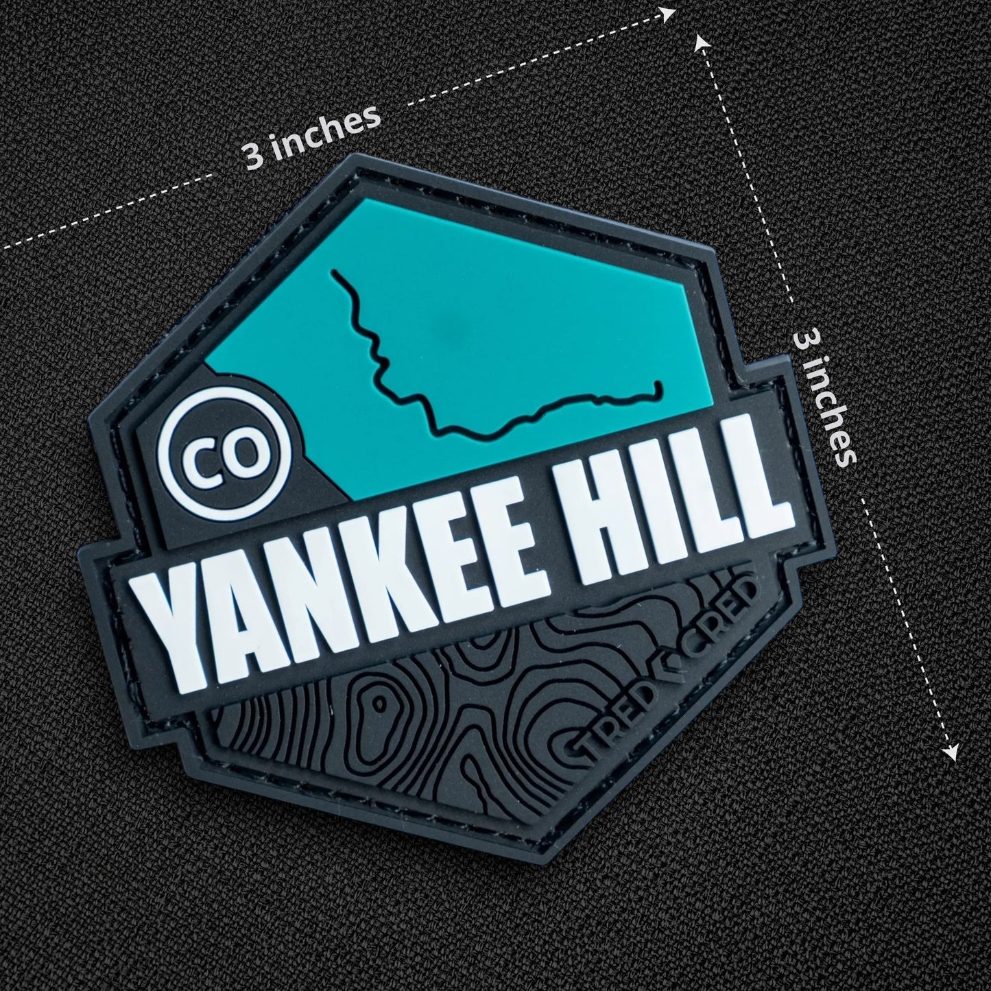 Tred Cred Yankee Hill trail patch in teal and black PVC rubber with a topographic map design and hook backing.